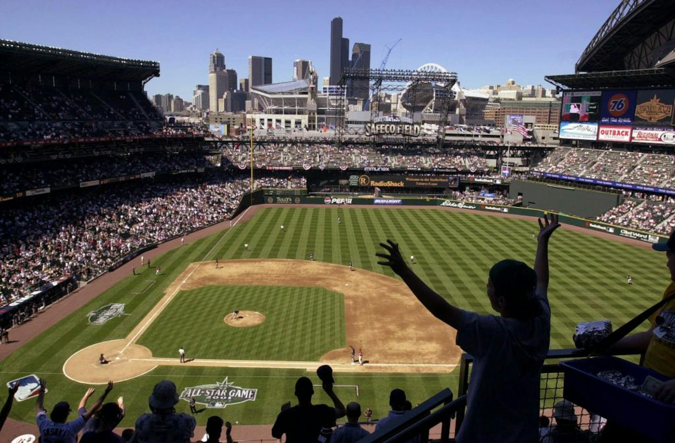 Fans stand and cheer during an All-Star Futures game Sunday, July 8, 2001 under clear skies and downtown Seattle in the background. The 2-year-old open air ballpark has changed the atmosphere of Seattle baseball in so many ways, something that will be very clear to fans tuning in to Tuesday's All-Star game, the biggest national stage yet for Safeco Field. Its manicured grass, vistas of downtown and Puget Sound, and unique international flavor are making many former Mariners just a little sorry t
