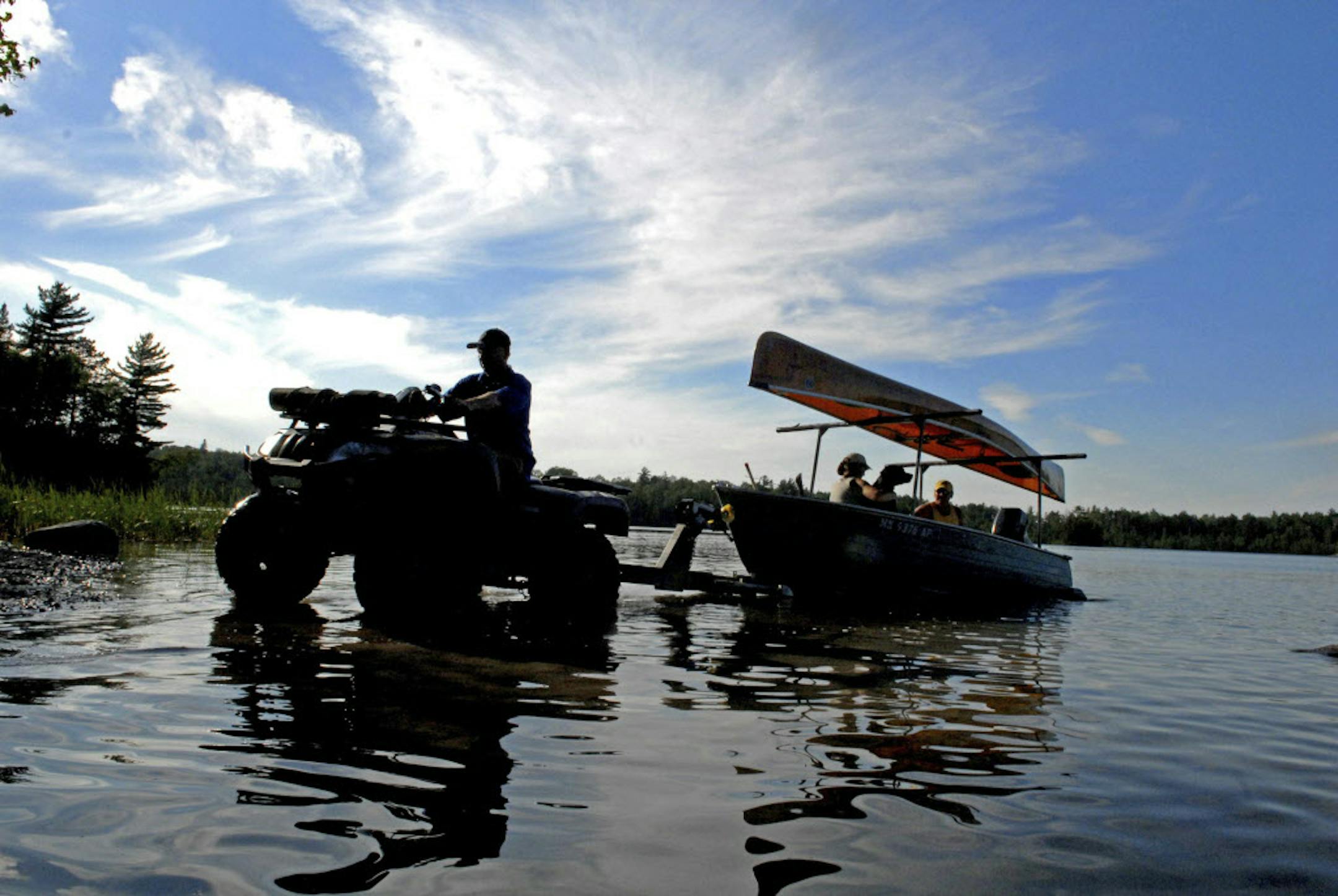 Trout Lake portage manager Jim Zak hooks up to a boat and its passengers ‚Äî a dog included ‚Äî in preparation of transferring one and all from Trout Lake in the Boundary Waters Canoe Area Wilderness to Lake Vermilion, which lies outside the wilderness area.