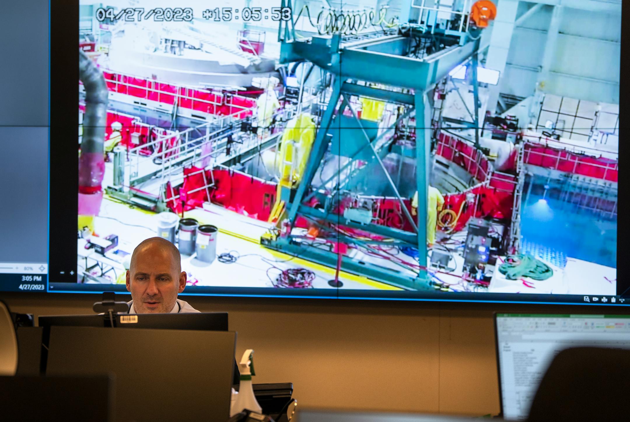 Plant manager Shawn Hafen, with live video of the reactor vessel seen behind him, works inside the outage control center at Xcel Energy Monticello Nuclear Generating Plant.