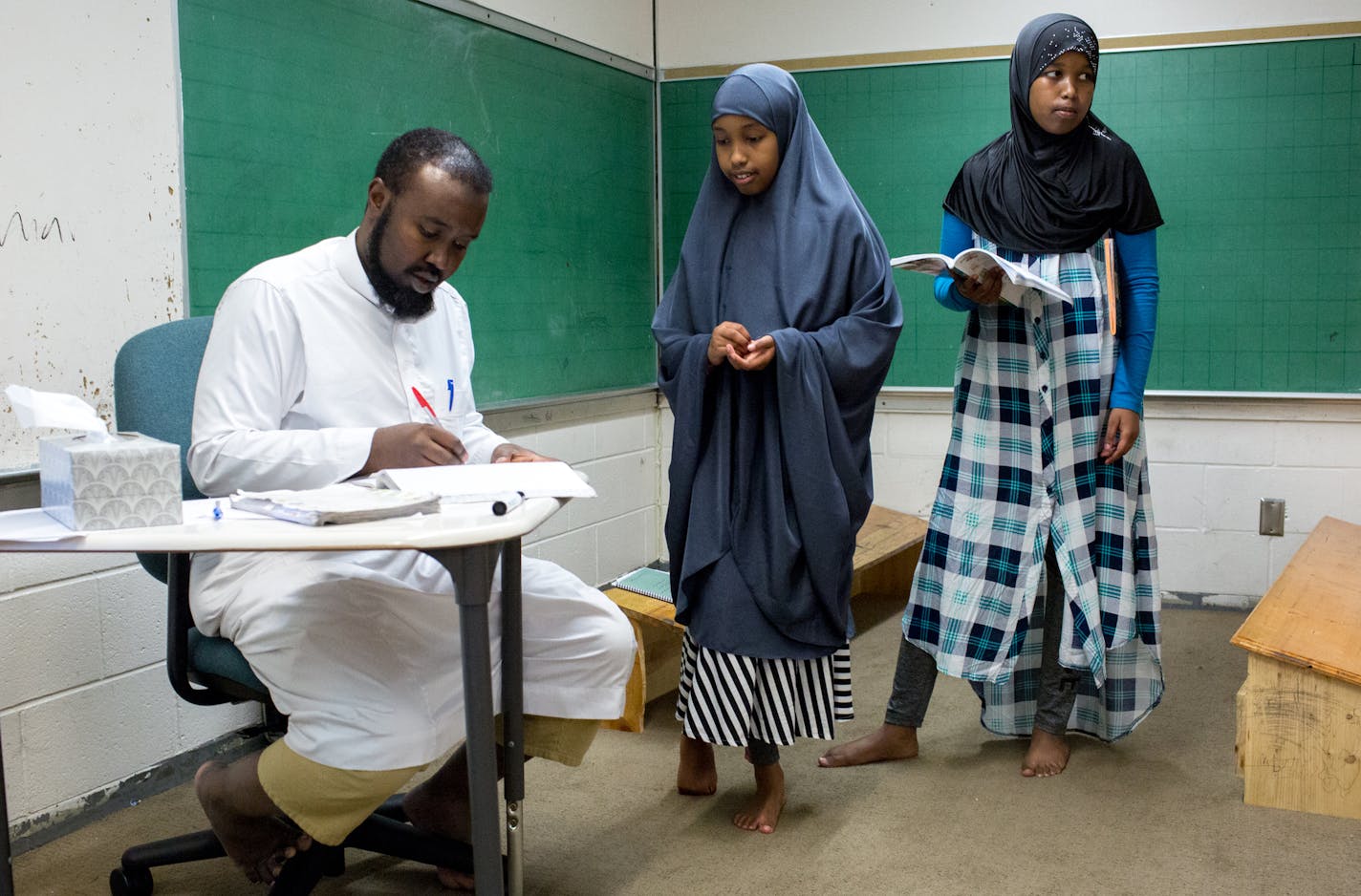 Amal, center at right, and Hamda Abdikader practice Arabic with Muse Hussein during class at the Dar Al Farooq Islamic Center on Monday.