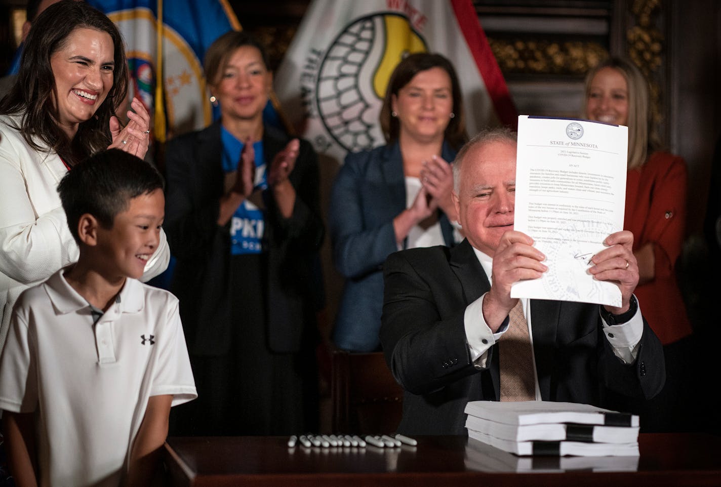 Minnesota Gov. Tim Walz flanked by Lieutenant Gov. Peggy Flanagan and Dylan Nguyen, 9, signed a $52 billion state budget bill. Dylan mom Hue Nguyen is the deputy chief of staff, policy and legislative affairs for Gov. Walz administration. (Jerry Holt/Star Tribune via AP)