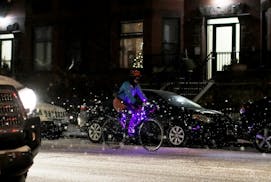 Amid falling snow Wednesday night a bicyclist with purple lights adorning her bike made her way along S. 9th St. in downtown Minneapolis.