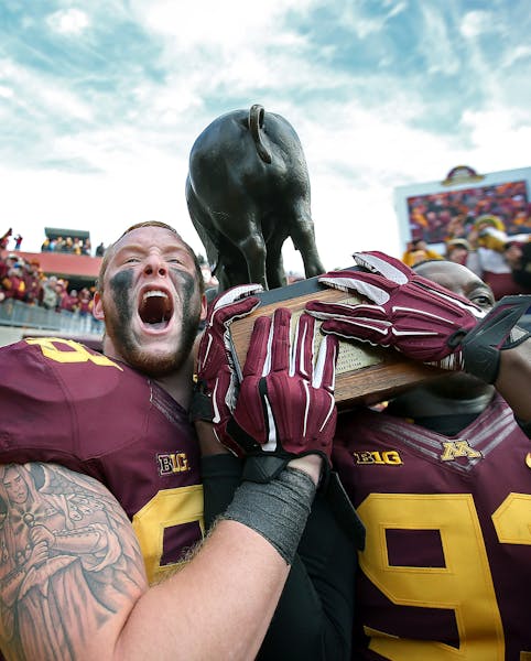 Gophers tight end Maxx Williams, left, and defensive lineman Ben Perry celebrated with the Floyd of Rosedale trophy after the Gophers defeated Iowa 51