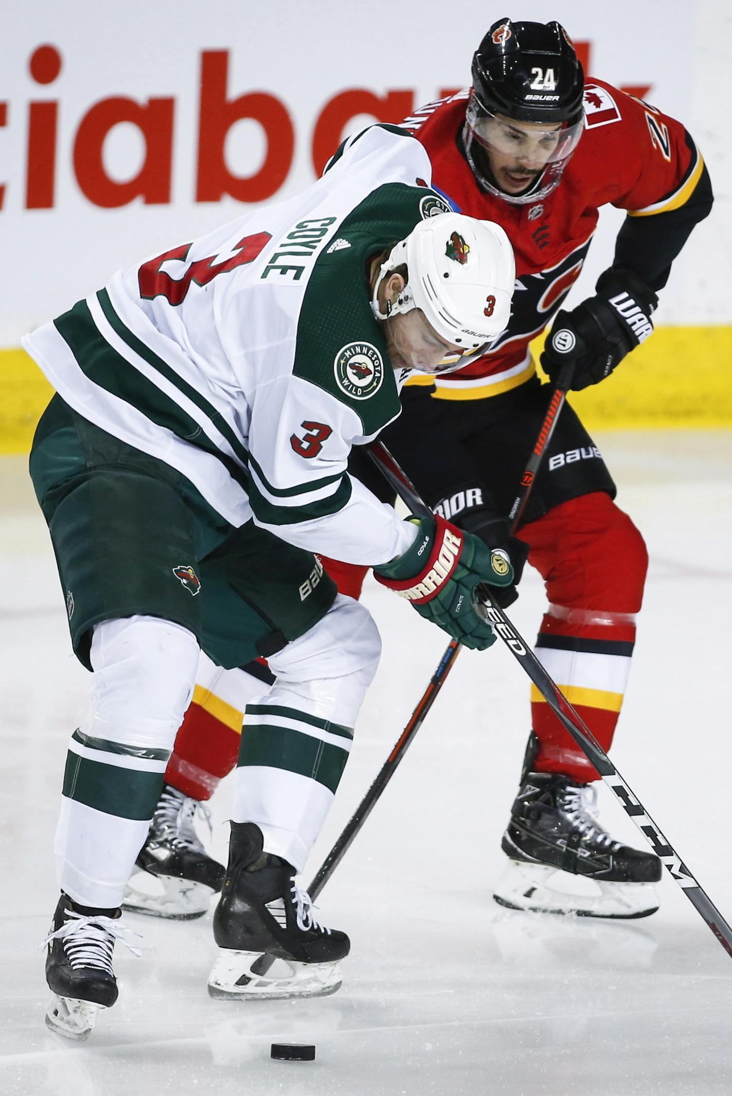 Minnesota Wild's Charlie Coyle, left, and Calgary Flames' Travis Hamonic battle for the puck during first-period NHL hockey game action in Calgary, Alberta, Thursday, Dec. 6, 2018. (Jeff McIntosh/The Canadian Press via AP)