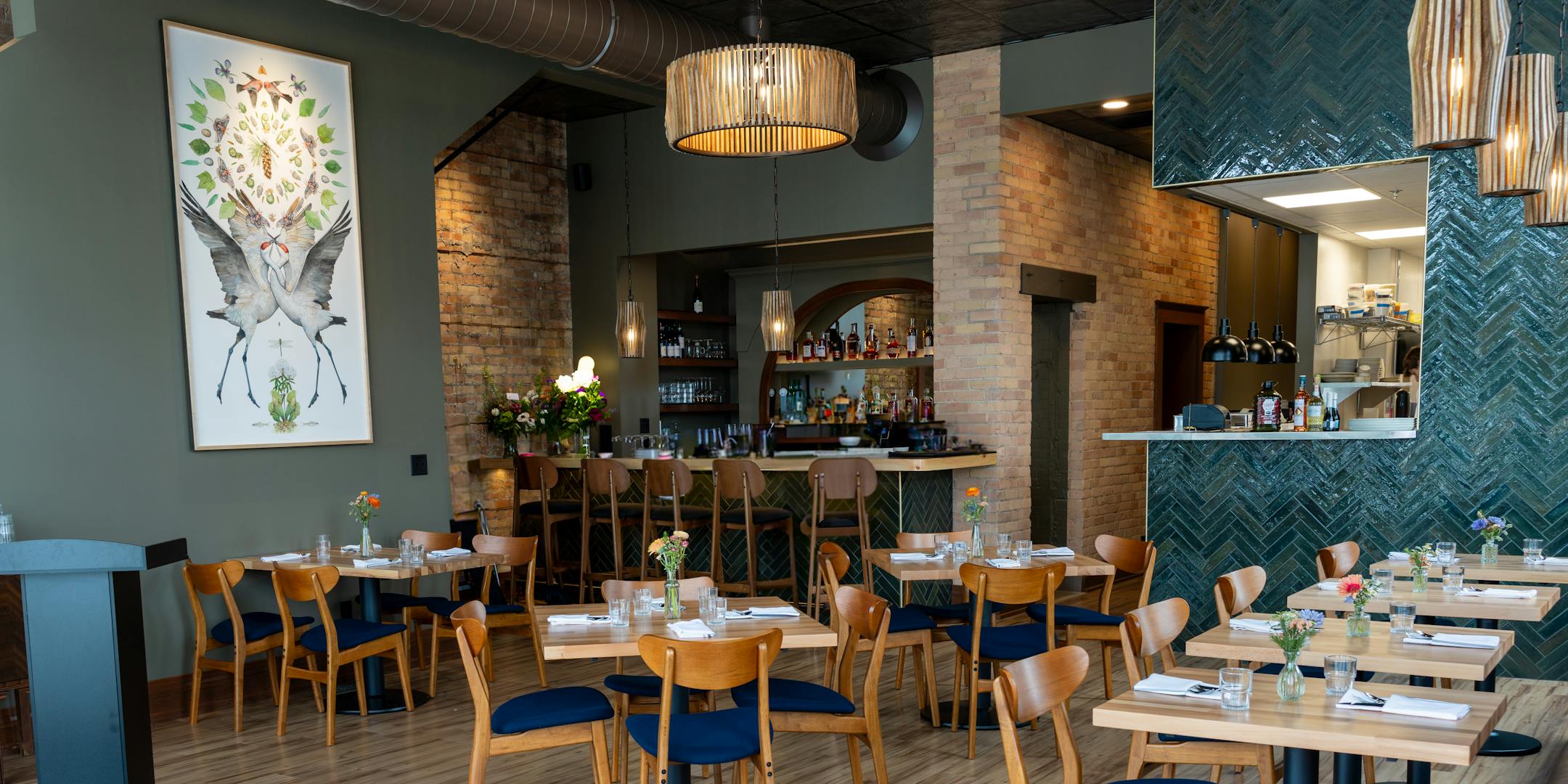 Dining room set with Scandinavian teak chairs and tables, accented by an aquamarine tile accent wall leading into the kitchen.