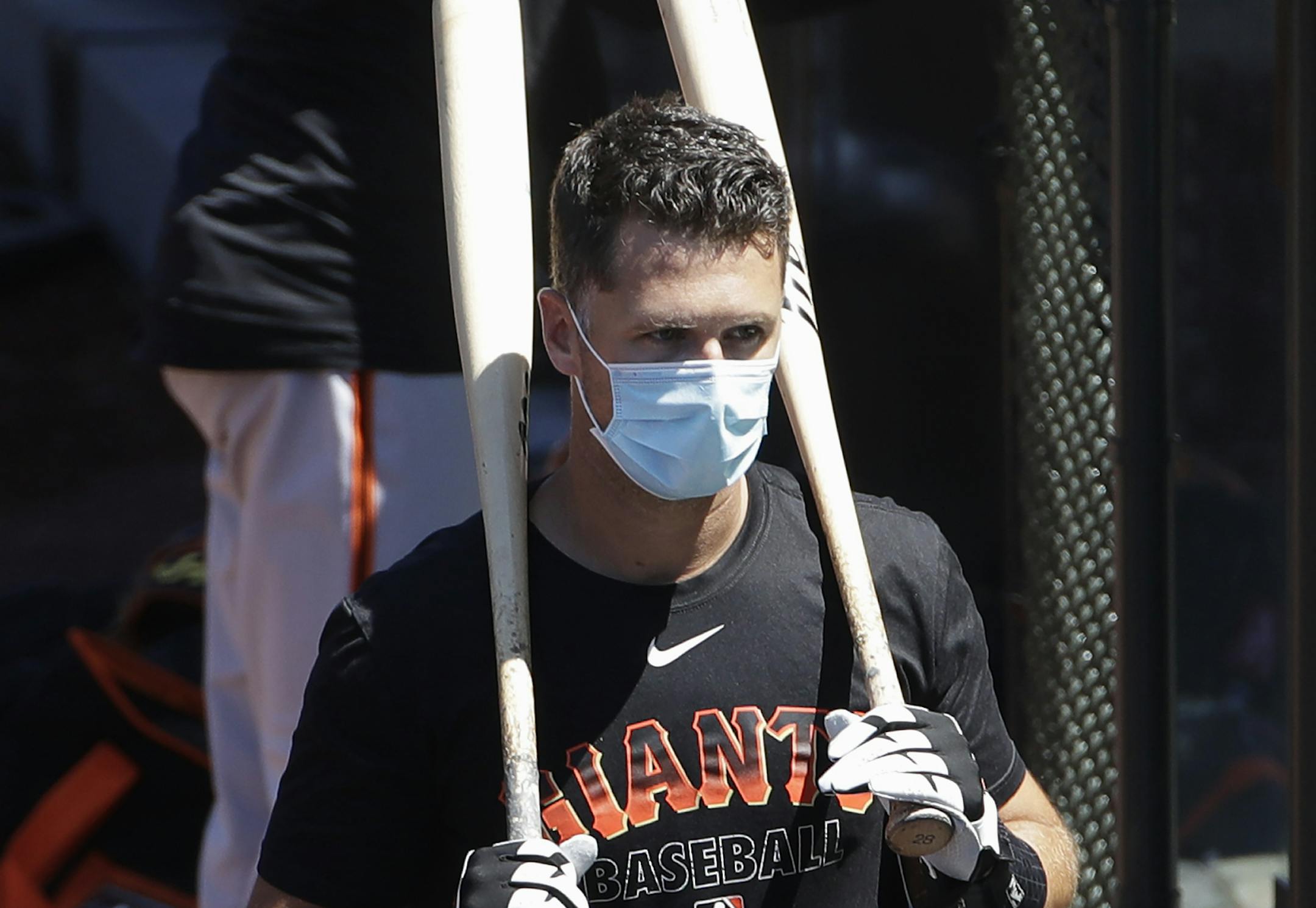 FILE - In this Sunday, July 5, 2020, file photo, San Francisco Giants' Buster Posey carries his bats during a baseball practice in San Francisco. Posey is the latest big-name player to skip this season because of concerns over the coronavirus pandemic. Posey announced his decision on Friday, July 10, 2020. He says his family finalized the adoption of identical twin girls this week. The babies were born prematurely and Posey said after consultations with his wife and doctor he decided to opt out