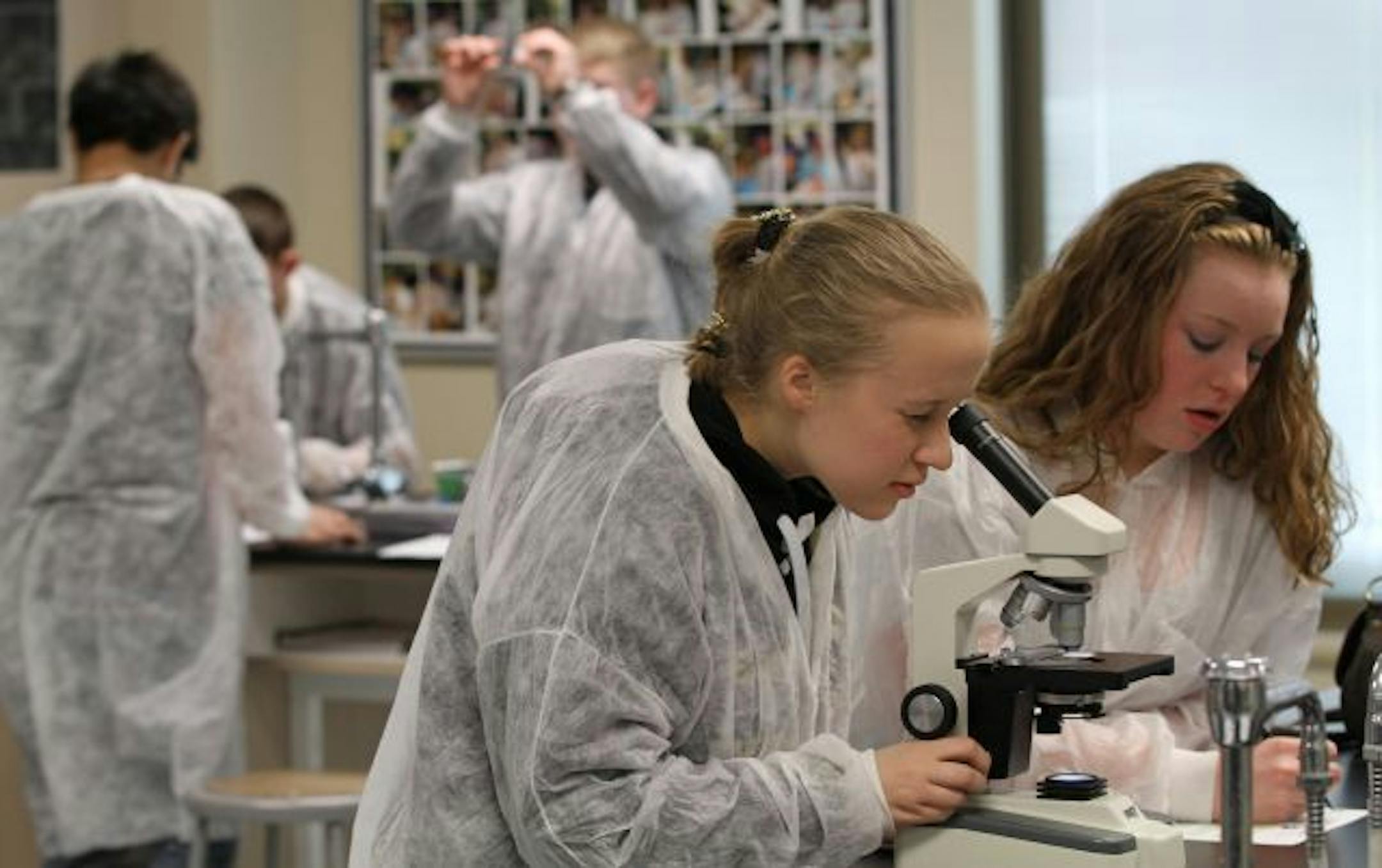 East Ridge High School students (center) Emily Benson and (right) Taylor Johnson used a microscope to look at slides of sickle cell anemia and healthy cells during Nancy Berg's Principals fo Bio-Medical Science class. The course, one of the first in the nation, offers students the opportunity to learn about medicine and is funded by 3M.