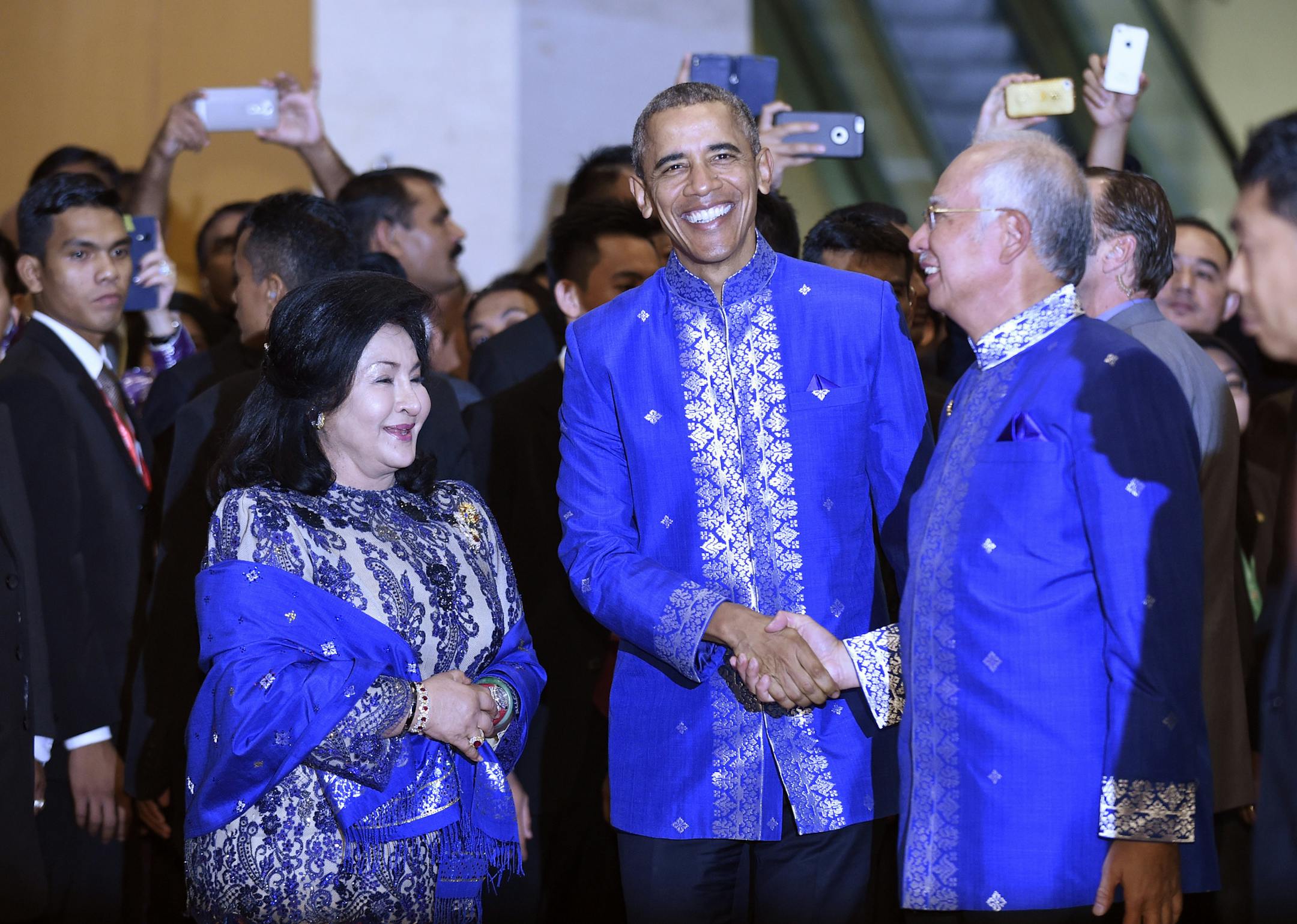 President Barack Obama, center, shakes hands with Malaysia’s Prime Minister Najib Razak, right, as Najib's wife Rosmah Mansor watches at left after arriving for the East Asia Summit gala dinner in Kuala Lumpur, Malaysia, Saturday, Nov. 21, 2015. (AP Photo/Susan Walsh)