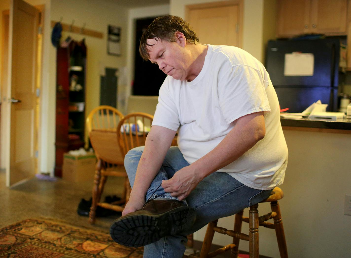 Brad Teslow, a former gym teacher,ties his shoes at his apartment before heading to work Wednesday, Feb. 27, 2016, in St. Paul, MN. ](DAVID JOLES/STARTRIBUNE)djoles@startribune.com Brad Teslow will be preparing for work at a sheltered workshop. He will be leaving his downtown apartment in St. Paul at 3 p.m., and then driving to Bloomington, where he works on an assembly line in a warehouse operated by Opportunity Partners**Brad Teslow,cq