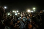 This image won the World Press Photo of the Year award. A young man, illuminated by mobile phones, recites protest poetry while demonstrators chant sl