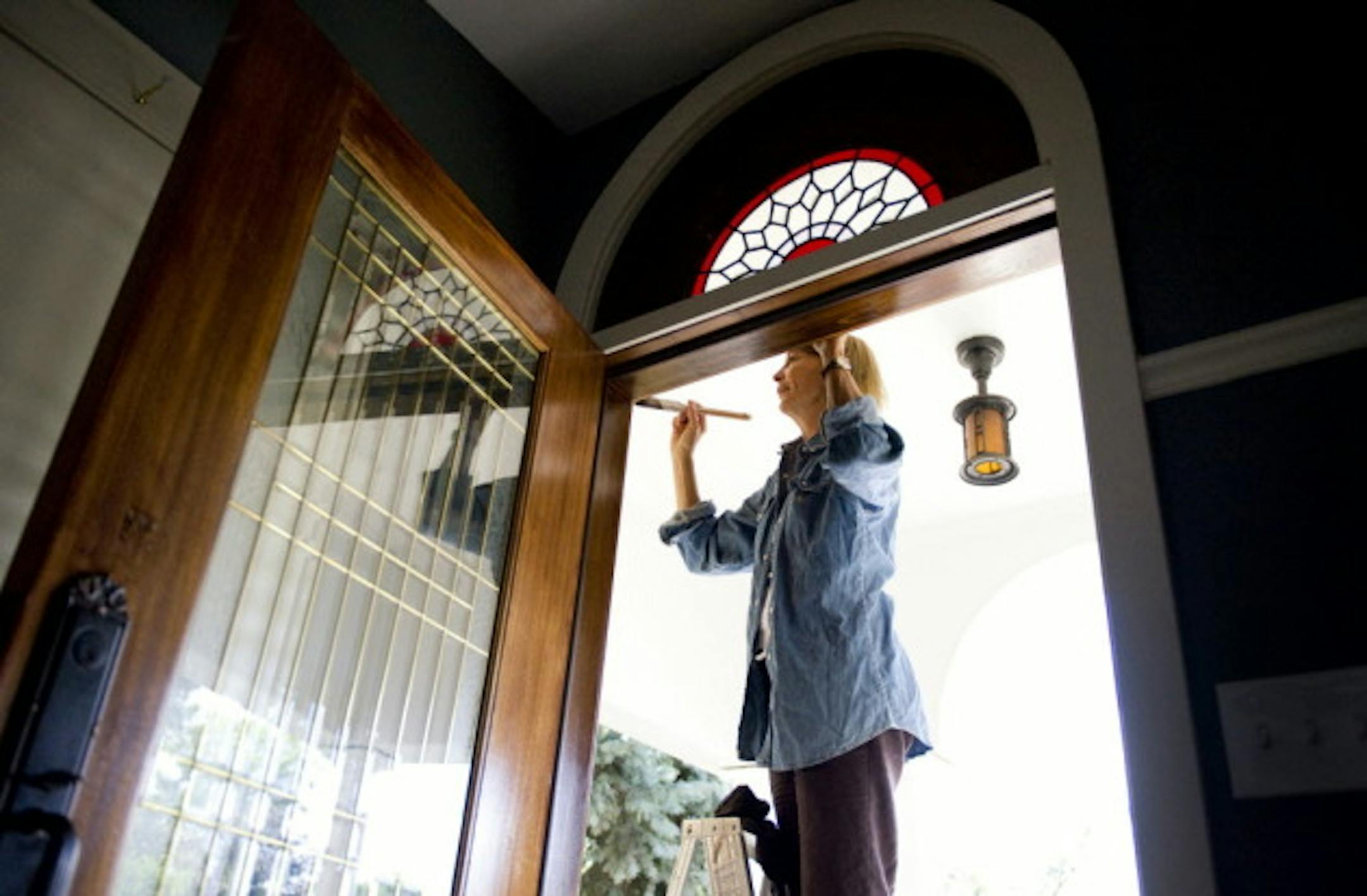 Mary Leer does touch-up work on the front door of a house she recently sold in North Minneapolis.