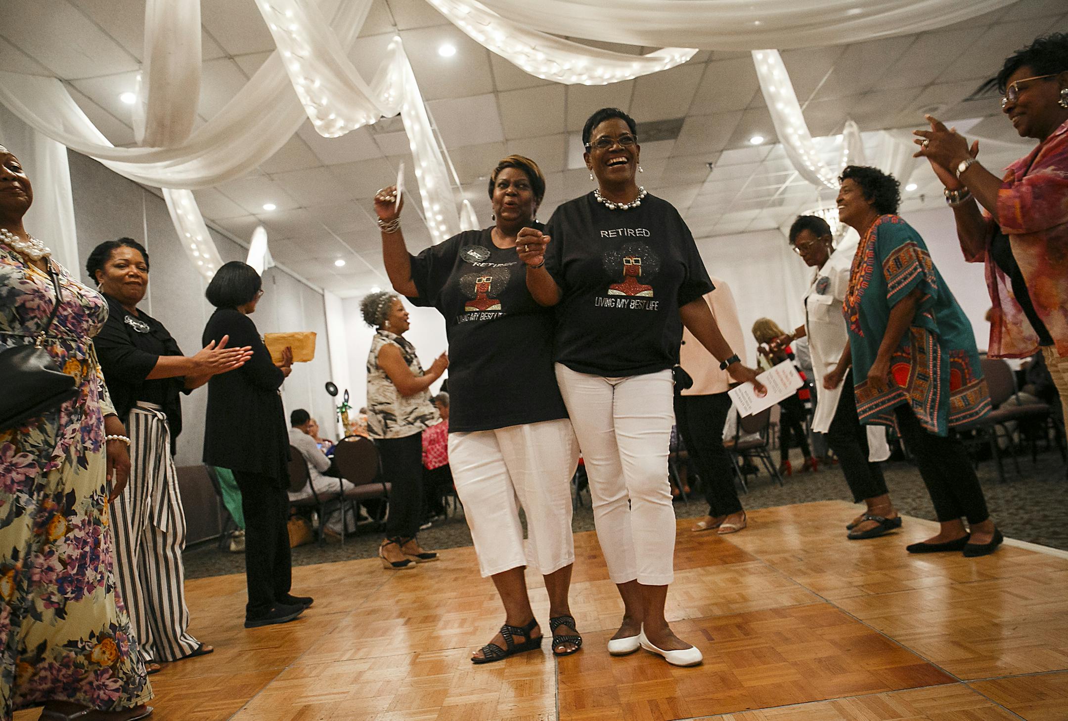 In their matching "retired and living my best life" shirts, Inez Blount-Mason and Mona Gunn take their turn in the soul train line during Not Back to School luncheon held at Grand Affairs in Virginia Beach, Va., on Tuesday, September 3, 2019. (Kristen Zeis/Virginian Pilot/TNS) ORG XMIT: 1418370 ORG XMIT: MIN1909091426268341