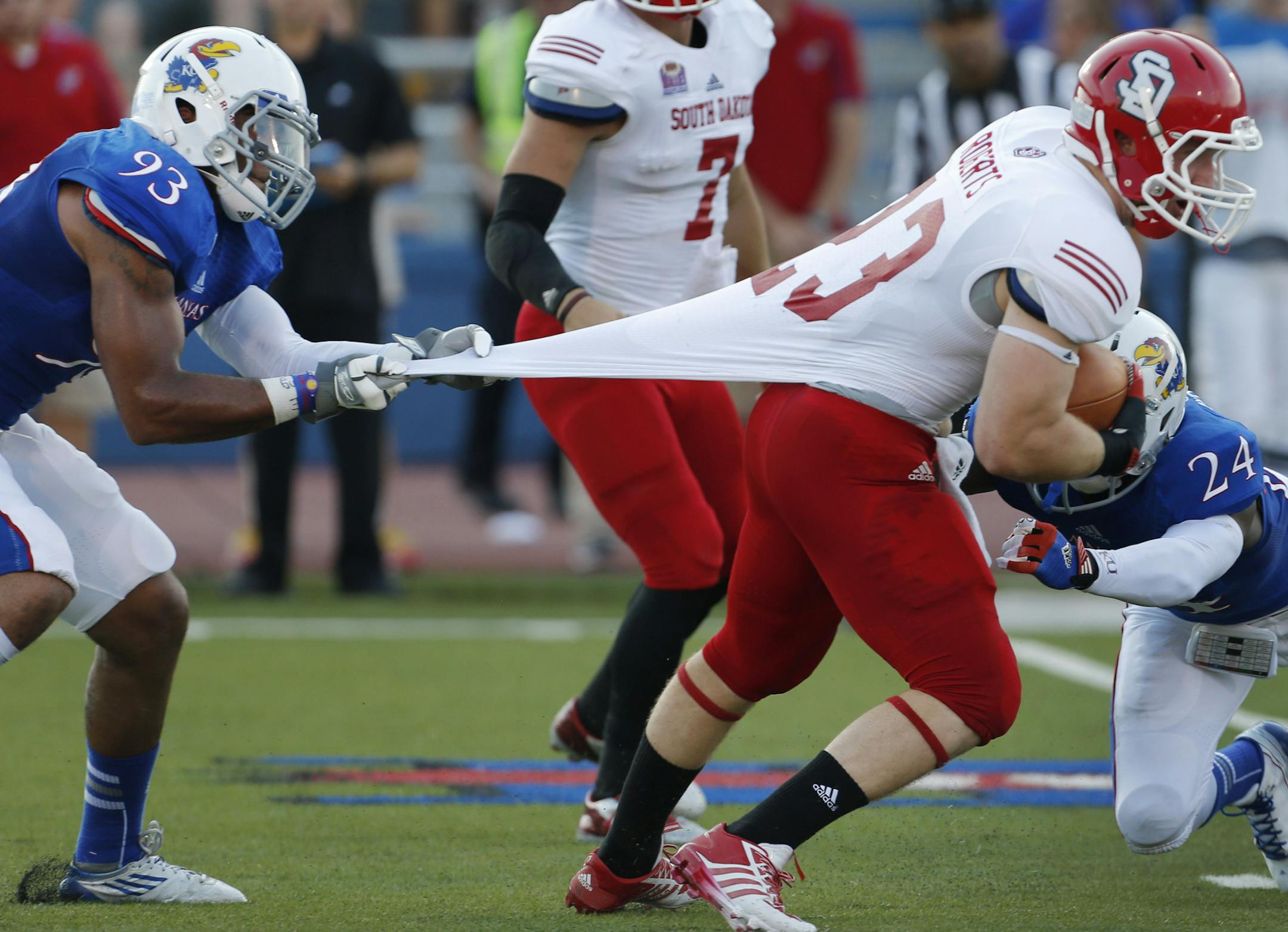 Kansas linebacker Ben Goodman (93) hangs on to South Dakota running back Jordan Roberts (23) until cornerback JaCorey Shepherd (24) can help with the tackle during the first half of an NCAA college football game in Lawrence, Kan., Saturday, Sept. 7, 2013. (AP Photo/Orlin Wagner)
