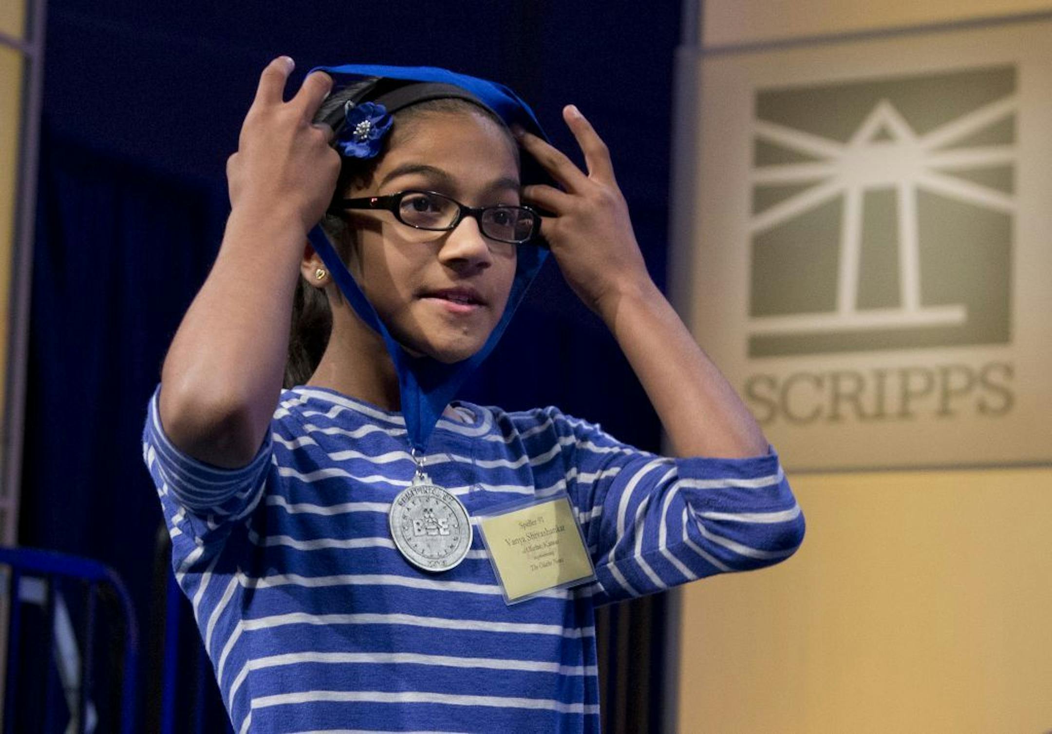 Vanya Shivashankar, of Olathe, Kan., puts on her medal after it was announced that she made the semifinal round of the National Spelling Bee on Wednesday, May 29, 2013, in Oxon Hill, Md. Shivashankar's sister, Kavya, won the Spelling Bee in 2009 and she is trying to become the first sibling of a champion to win the title.