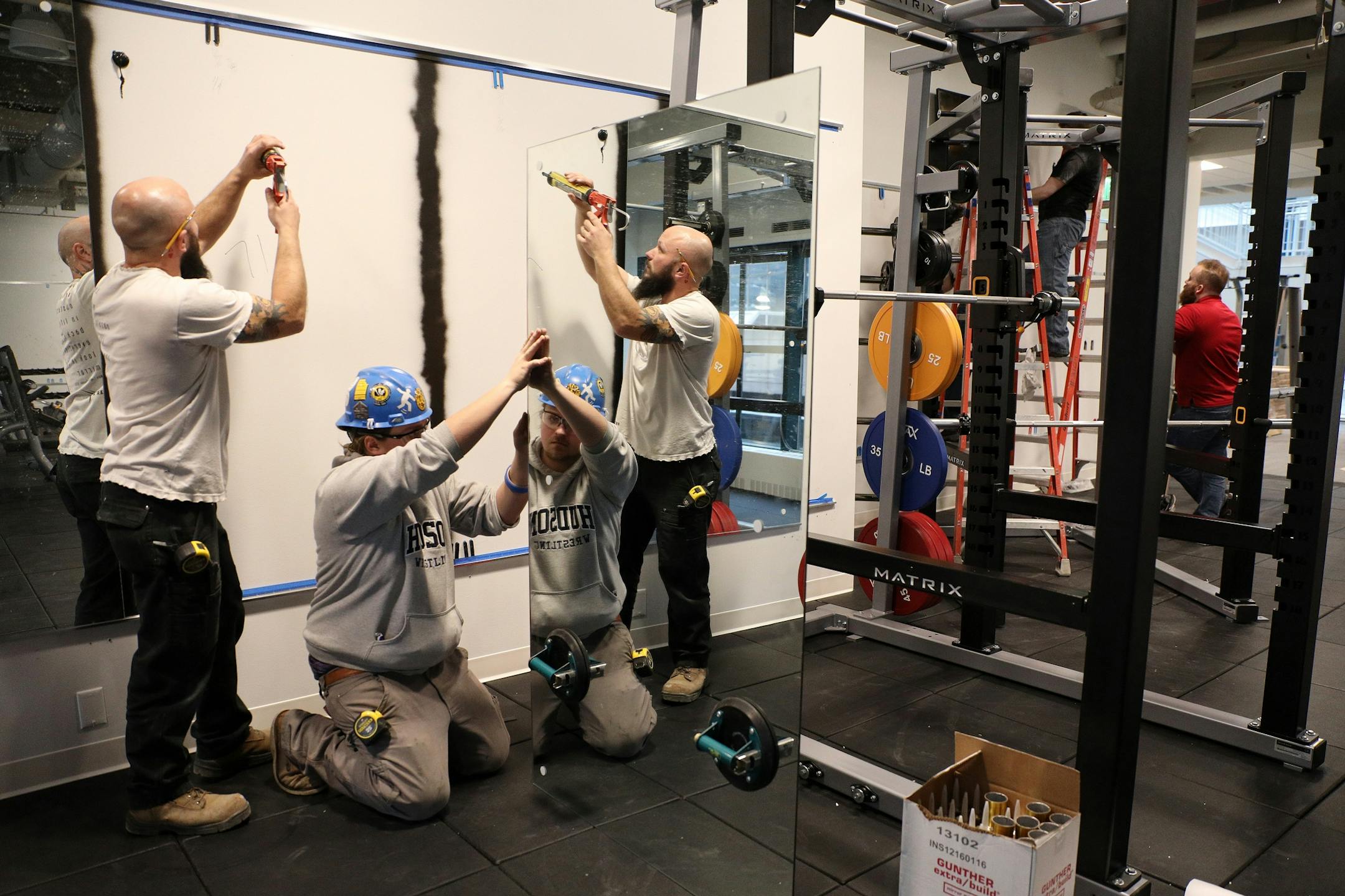 Glazers Tom Lamecker, left, and Brylen Mulvehill installed a set of mirrors in the weight room area.