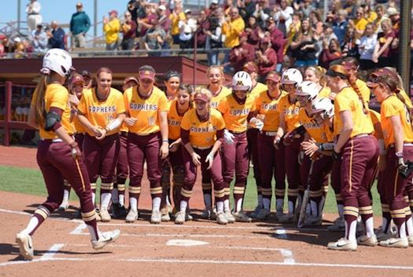 Teammates celebrated with Minnesota infielder Makenna Partain (3) after Partain's grand slam in the bottom of the first inning against Wisconsin.