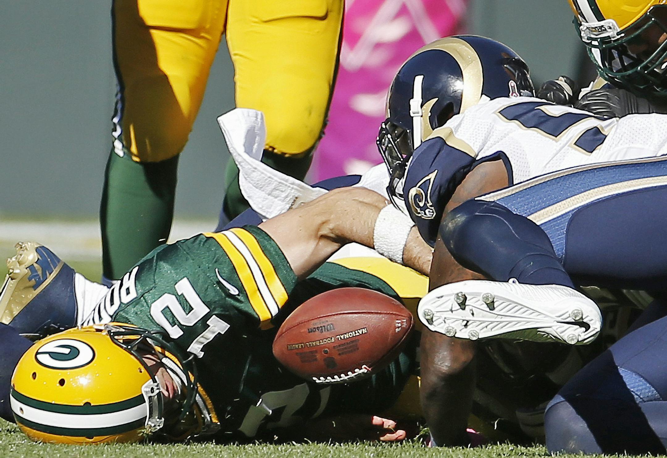 Green Bay Packers' Aaron Rodgers (12) fumbles the ball with St. Louis Rams' James Laurinaitis defending during the second half an NFL football game Sunday, Oct. 11, 2015, in Green Bay, Wis. The Rams recovered the fumble. (AP Photo/Morry Gash)