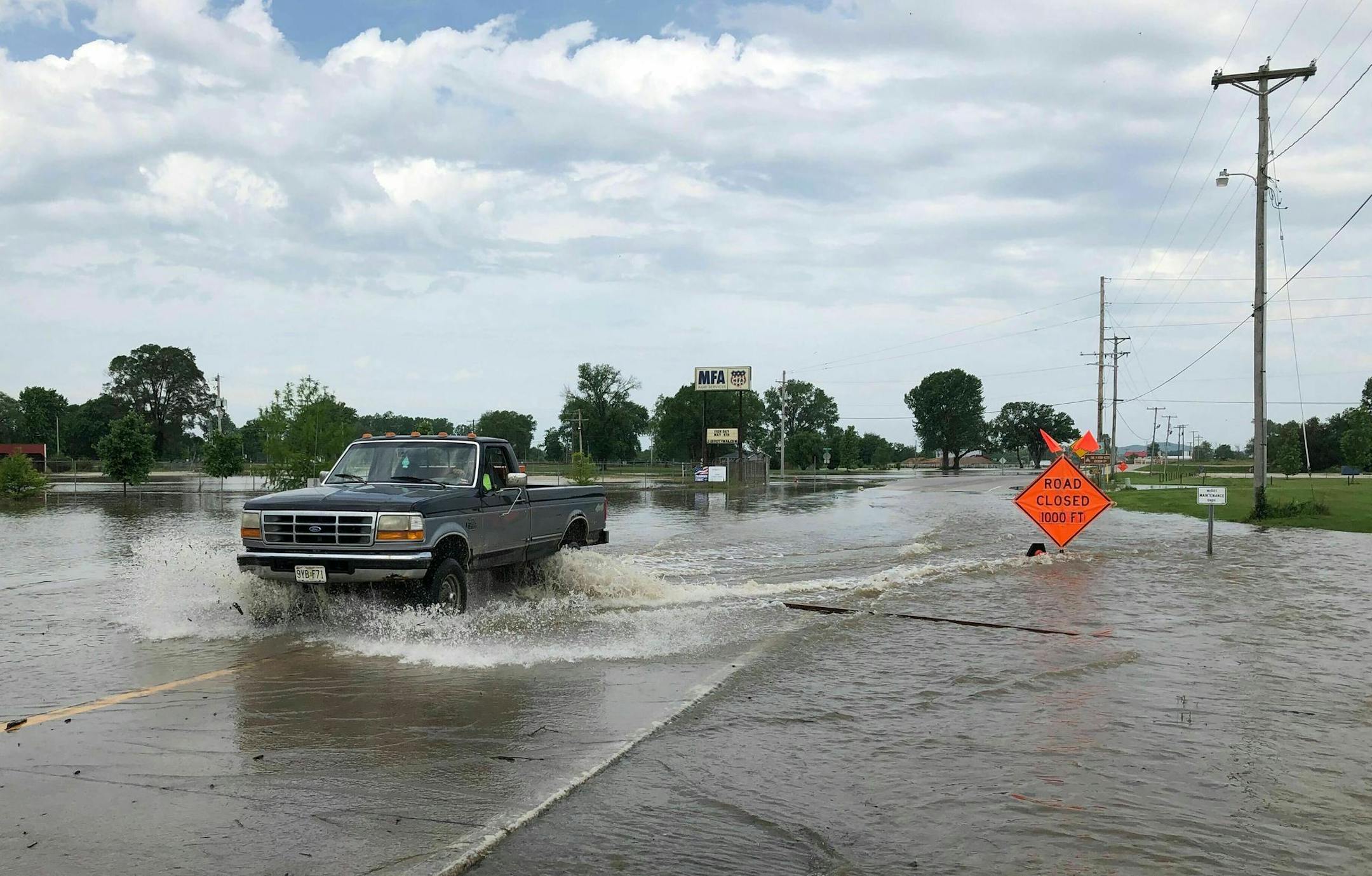 A pickup truck evacuates from an area in north Jefferson City Missouri as floodwaters from the Missouri River rise over the road on Friday, May 24, 2019. The flooding come as residents are still cleaning up from a powerful tornado that hit the state's capital city on May 22. (AP Photo/David A. Lieb)