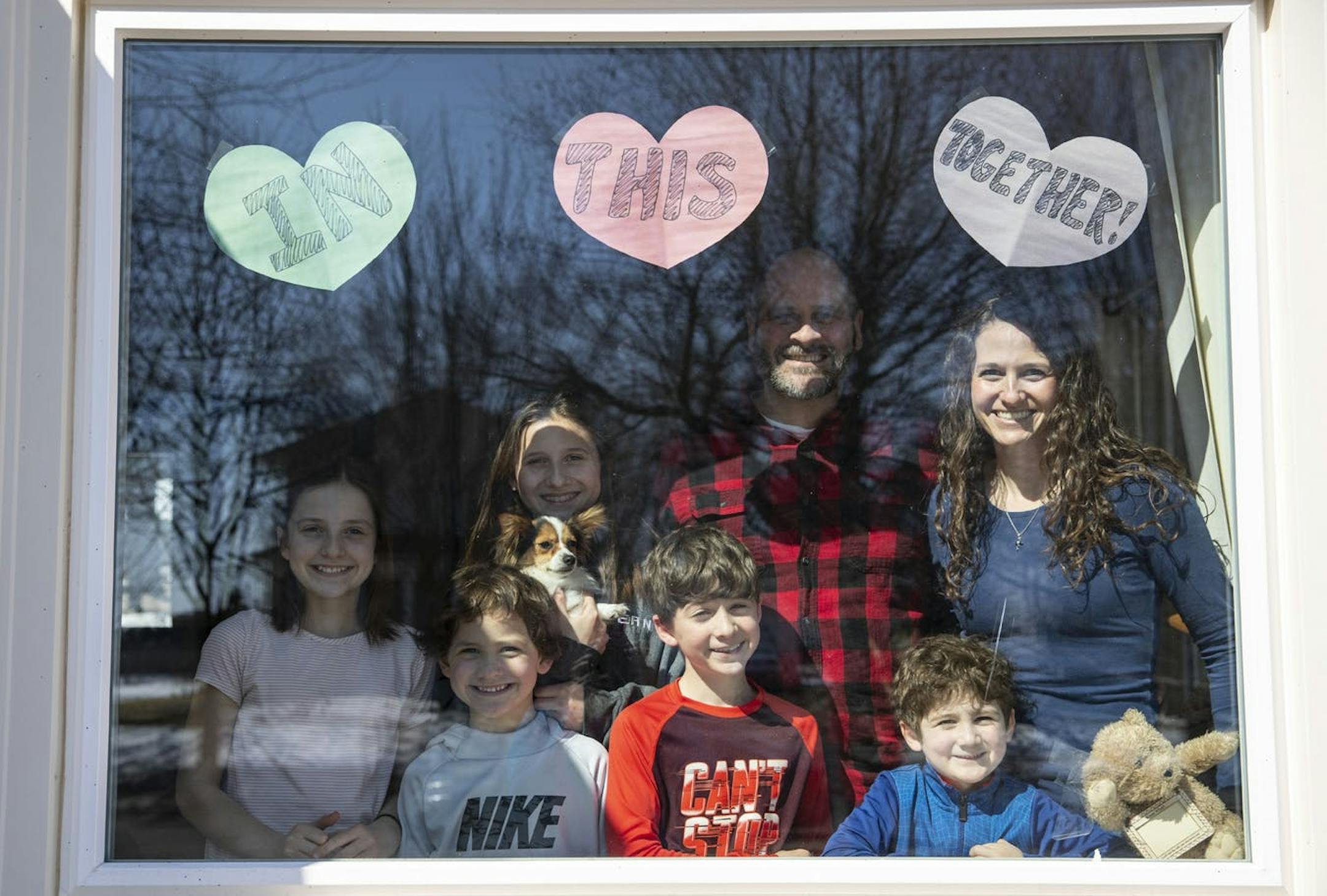 Liz and Kyle Eaton posed with their children, from left, Lydia, Michael, Annabelle, Luke and Josh and dog, Addy, in a window in their home in Duluth.