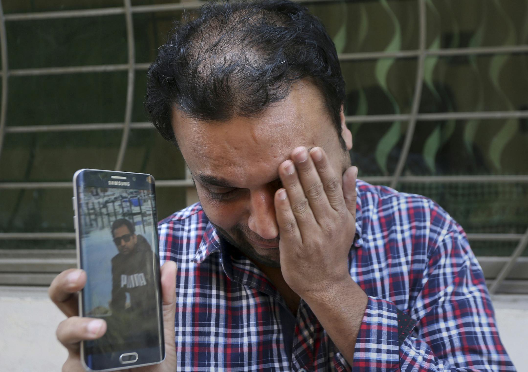 A relative weeps while showing the picture of Sohail Shahid, a Pakistani citizen who was killed in Christchurch mosque shootings, on his cell phone outside his home in Lahore, Pakistan, Sunday, March 17, 2019. Pakistan's foreign ministry spokesman says three more Pakistanis have been identified among the dead increasing the number of Pakistanis to nine killed in the mass shootings at two mosques in the New Zealand city of Christchurch. (AP Photo/K.M. Chaudary)