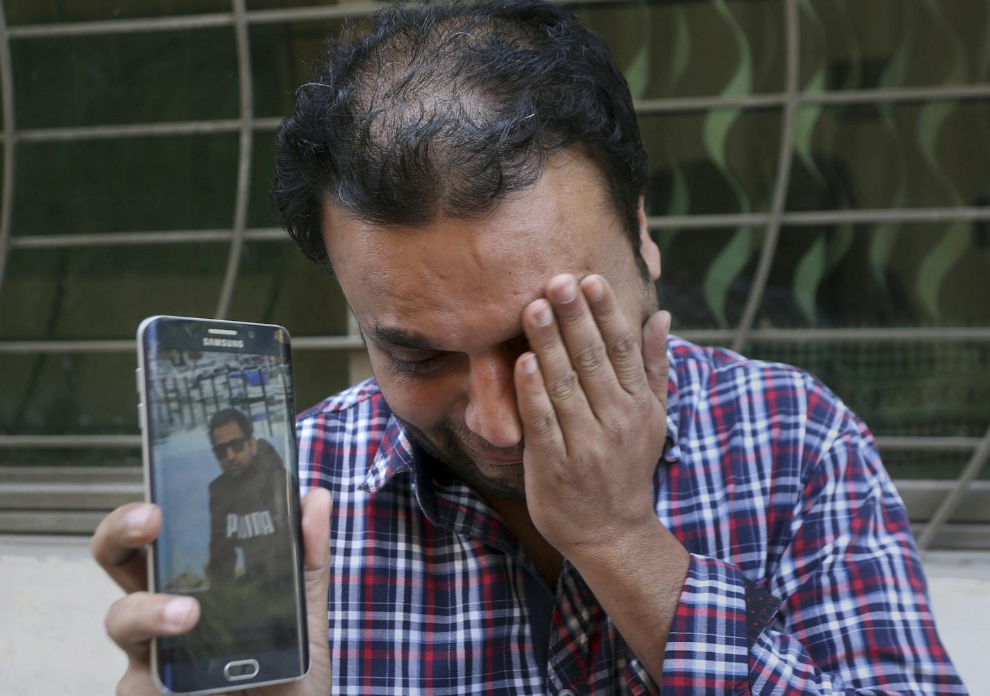 A relative weeps while showing the picture of Sohail Shahid, a Pakistani citizen who was killed in Christchurch mosque shootings, on his cell phone outside his home in Lahore, Pakistan, Sunday, March 17, 2019. Pakistan's foreign ministry spokesman says three more Pakistanis have been identified among the dead increasing the number of Pakistanis to nine killed in the mass shootings at two mosques in the New Zealand city of Christchurch. (AP Photo/K.M. Chaudary)