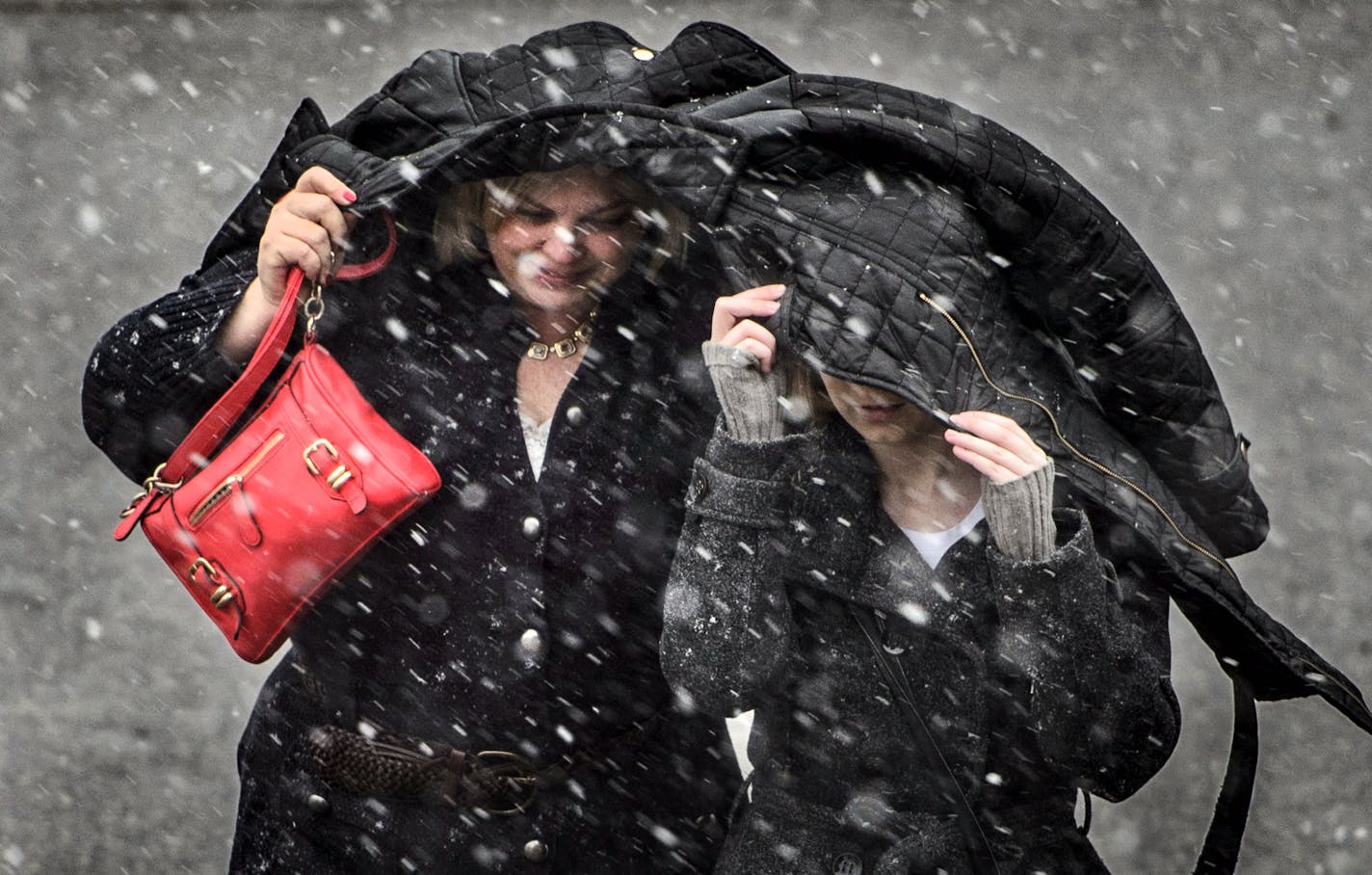 Jodi Walker-Robinson and her daughter Tori tried to fight off the fat wet snowflakes with a coat as they crossed Maple Street in River Falls, Wisconsin. Wednesday afternoon.