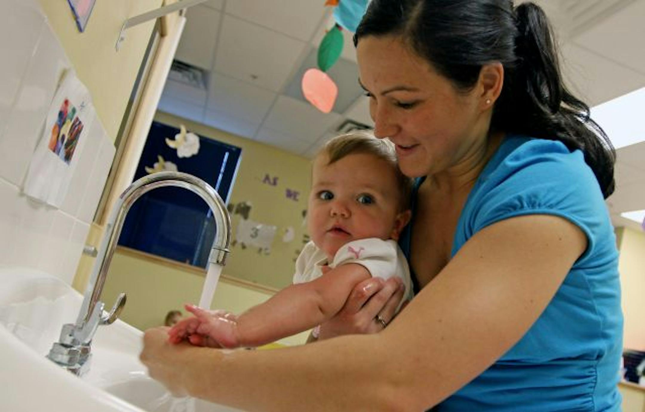 Kelli Labrosse washed 11-month-old Lily Cheney's hands at the Goddard School in Plymouth.