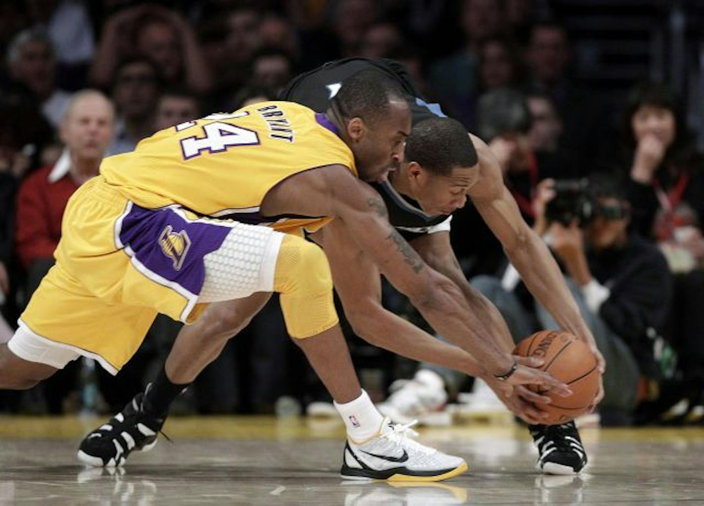 Los Angeles Lakers guard Kobe Bryant, left, and Minnesota Timberwolves forward Wesley Johnson fight for a loose ball during the first half of an NBA basketball game in Los Angeles, Friday, March 18, 2011.