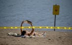 Rachel Soukup, cq, who was more than happy to take in the sun and a book, was also surprised to see very few people at Lake Nokomis beach, Friday, Aug