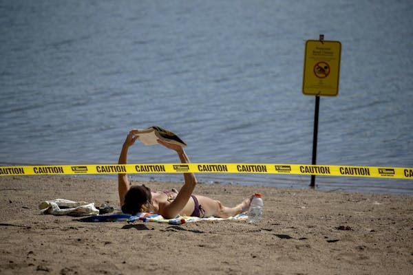Rachel Soukup, cq, who was more than happy to take in the sun and a book, was also surprised to see very few people at Lake Nokomis beach, Friday, Aug