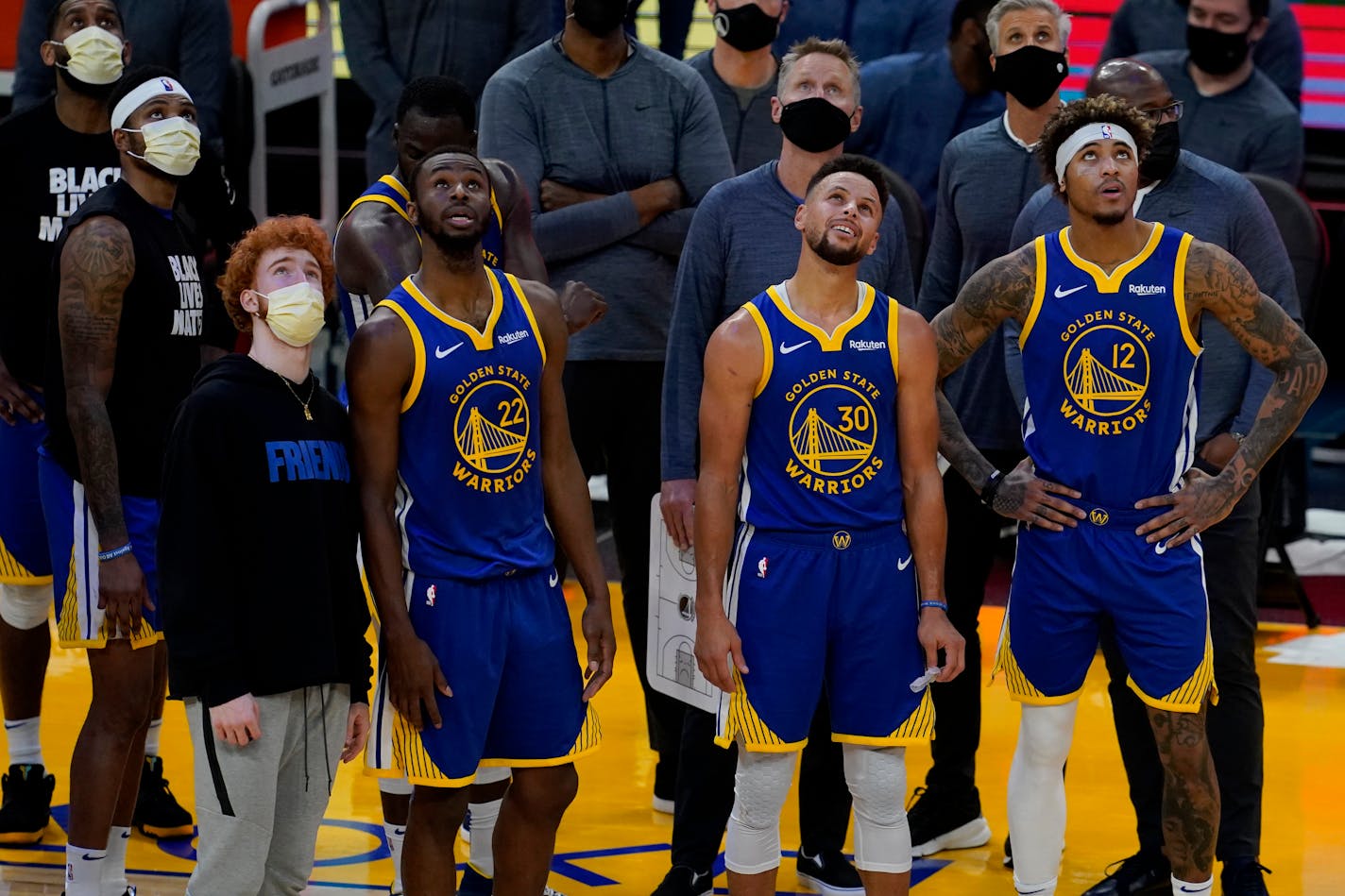 Andrew Wiggins (22), Stephen Curry (30) and Kelly Oubre Jr. (12) watch a replay on the scoreboard with head coach Steve Kerr, middle top, against the Pacers on Jan. 12