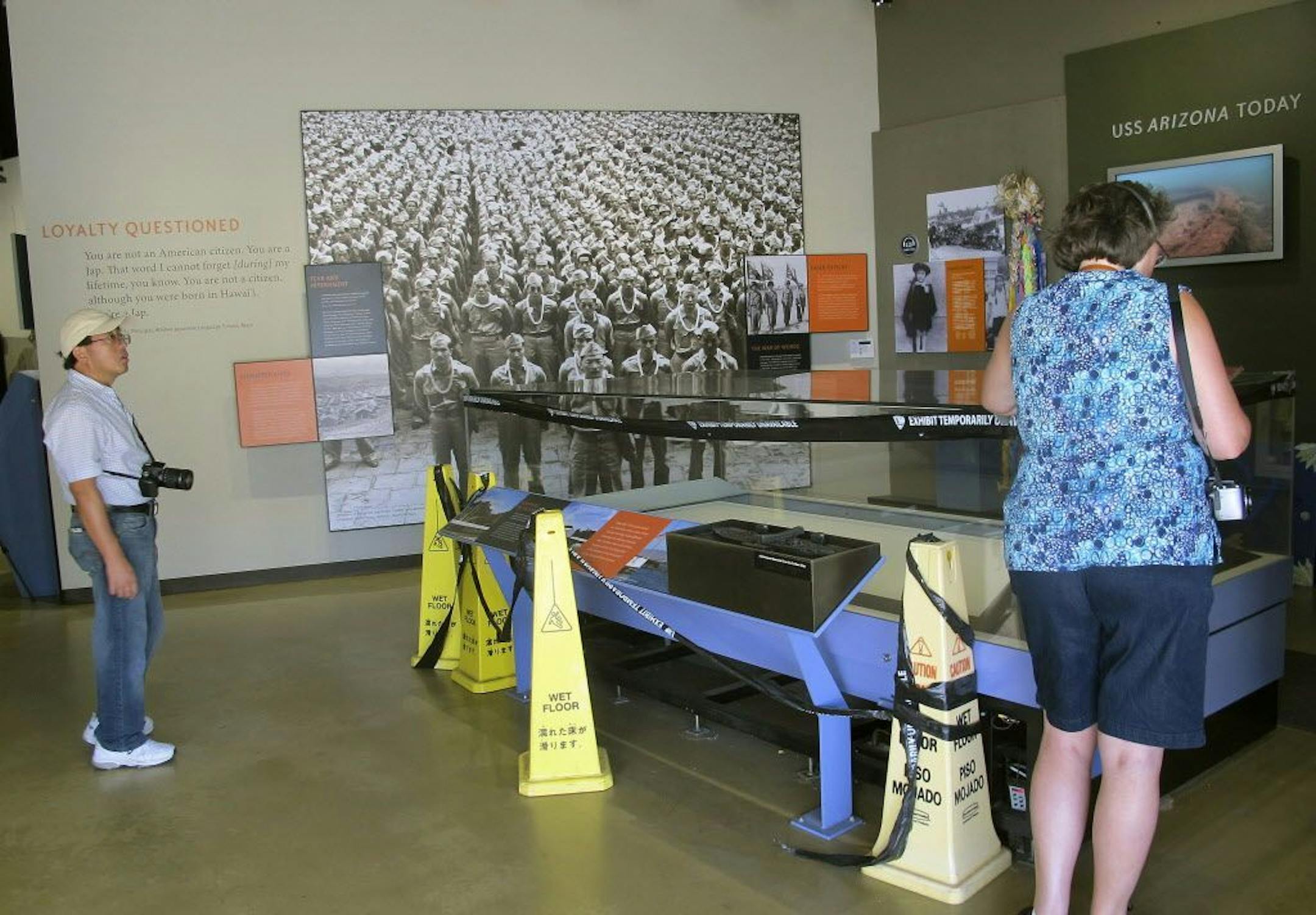 Visitors look at a glass exhibit case that has been empty for a year inside a museum at the visitors' center for the USS Arizona Memorial in Pearl Harbor, Hawaii.