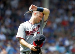 Minnesota Twins first baseman Joe Mauer wipes the sweat from his face during the second inning of a baseball game against the Chicago Cubs, Saturday, 