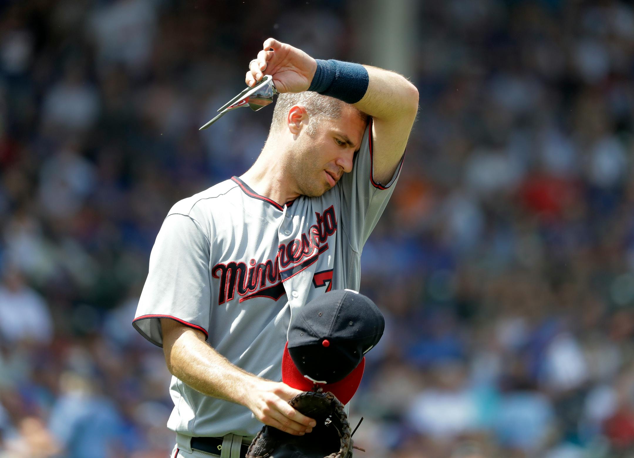 Minnesota Twins first baseman Joe Mauer wipes the sweat from his face during the second inning of a baseball game against the Chicago Cubs, Saturday, June 30, 2018, in Chicago. Temperatures at Wrigley Field climbed into the 90's with a heat index of over 100 degrees. (AP Photo/Charles Rex Arbogast)