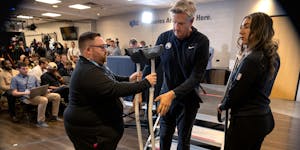 Timberwolves media relations officials Aaron Freeman, right, and Sara Perez help coach Chris Finch with his crutches during pregame availability in De