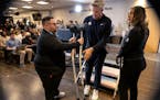 Timberwolves media relations officials Aaron Freeman, right, and Sara Perez help coach Chris Finch with his crutches during pregame availability in De