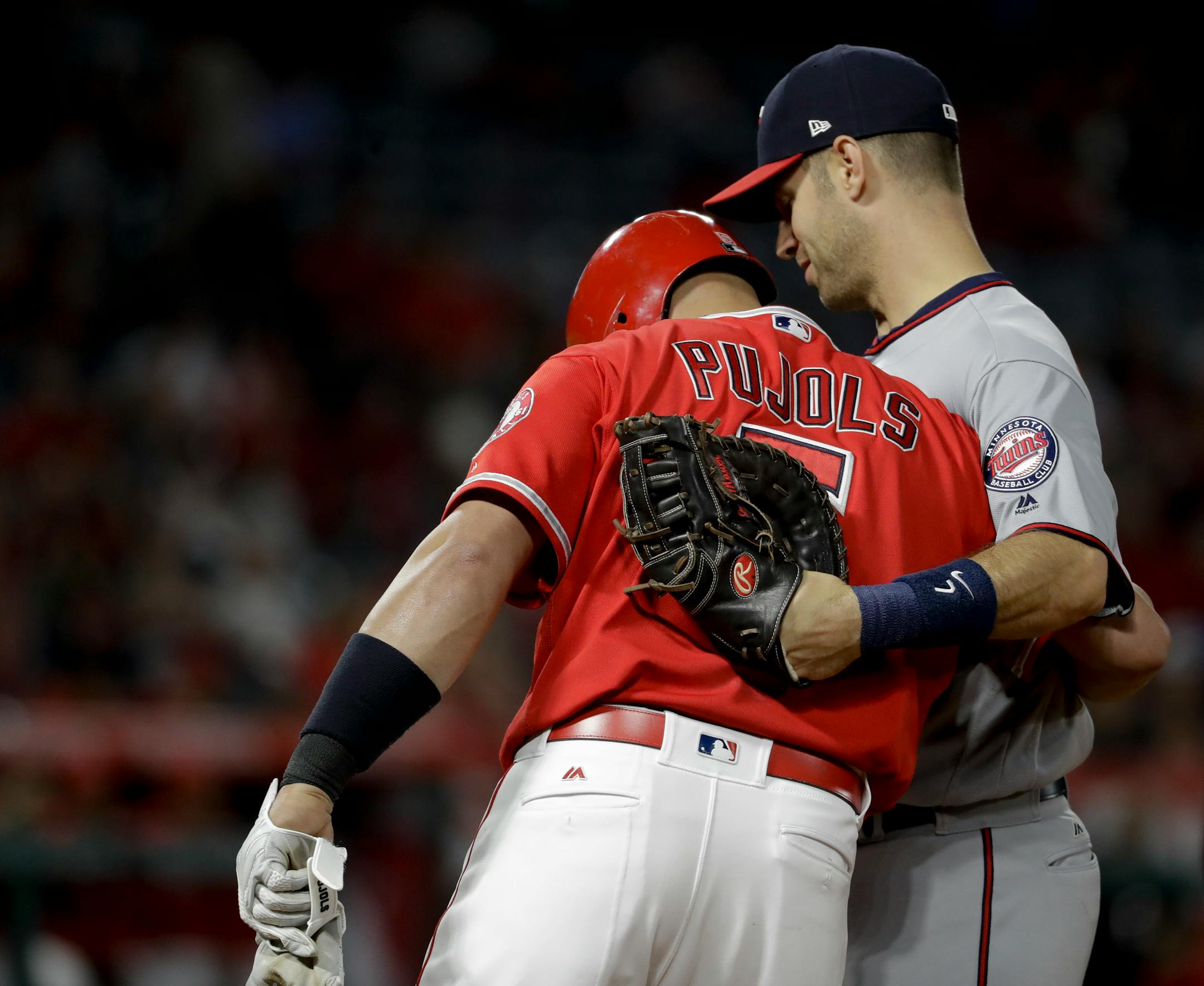 Los Angeles Angels' Albert Pujols, left, gets a hug from Minnesota Twins first baseman Joe Mauer after a base hit during the fourth inning of a baseball game in Anaheim, Calif., Thursday, June 1, 2017. (AP Photo/Chris Carlson)