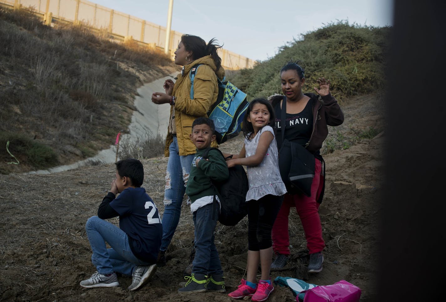 In a photo taken from the Tijuana, Mexico, side of the border, Honduran migrants react as they surrender to the U.S. Border Patrol after crossing the border wall in to the United States, Sunday, Dec. 2, 2018. Thousands of migrants who traveled via caravan are seeking asylum in the U.S., but face a decision between waiting months or crossing illegally, because the U.S. government only processes a limited number of cases a day at the San Ysidro border crossing in San Diego. (AP Photo/Ramon Espinos