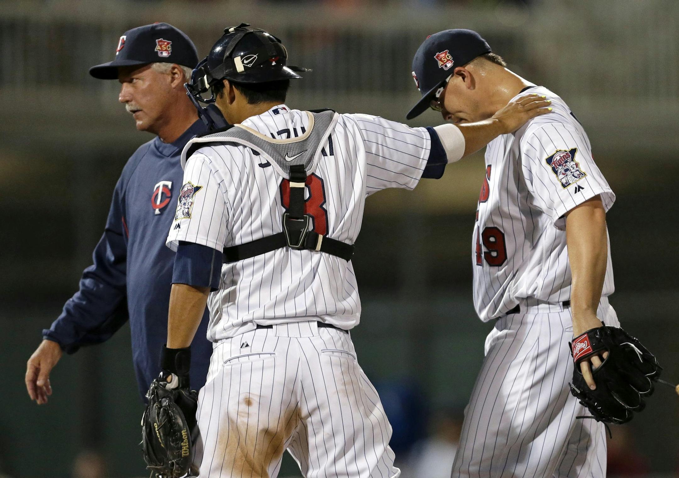 Minnesota Twins starting pitcher Vance Worley (49) gets a pat on the shoulder from catcher Kurt Suzuki (8) during a visit to the mound by pitching coach Rick Anderson in the third inning of an exhibition baseball game in Fort Myers, Fla., Tuesday, March 18, 2014. (AP Photo/Gerald Herbert)