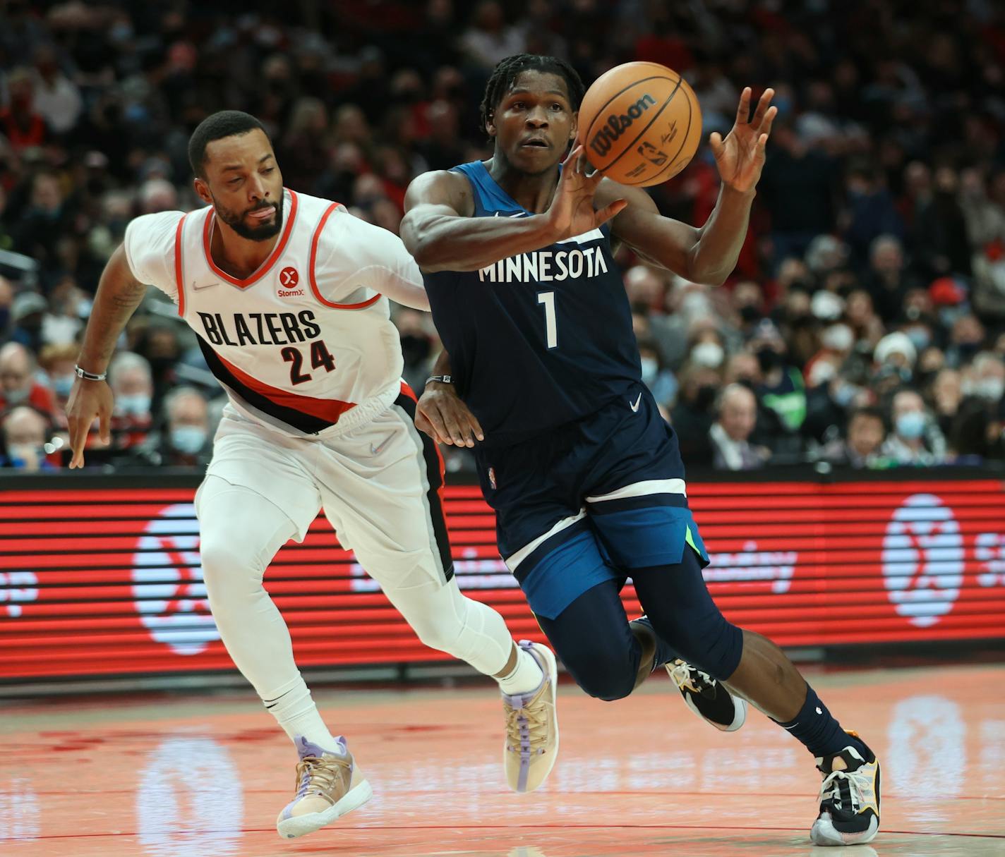 Minnesota Timberwolves forward Anthony Edwards, right, passes the ball as Portland Trail Blazers forward Norman Powell, left, defends during the second half of an NBA basketball game in Portland, Ore., Sunday, Dec. 12, 2021. Minnesota defeated Portland 116-111. (AP Photo/Steve Dipaola)