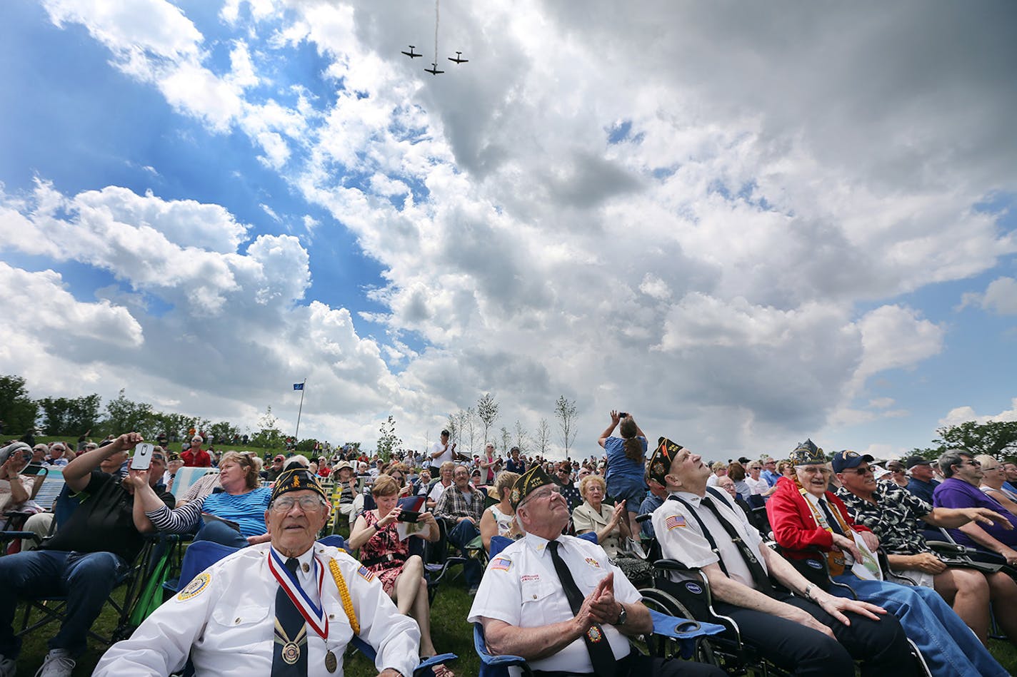 Minnesota veterans Norbert Skaran, left, WW II, Roger Tangen, Vietnam, Dale Wondrasch, Korea, and Malcolm Goodman, WW II, watched a flyover of WW II aircraft at the Minnesota State Veterans Cemetery Sunday, May 29, 2016, in Preston, Minn.