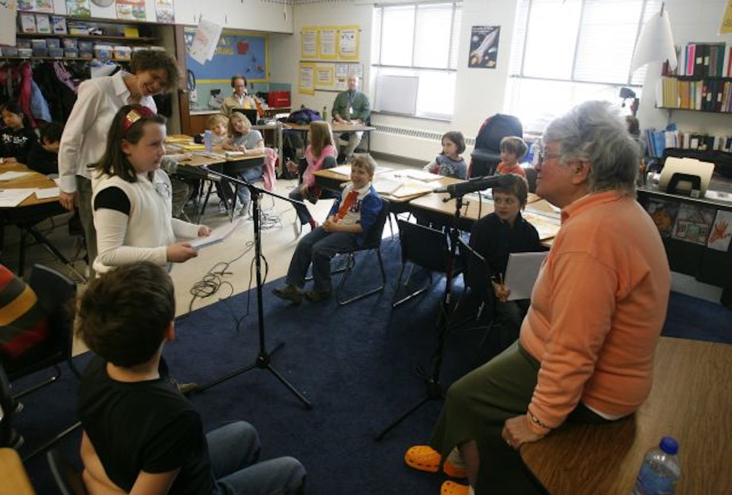 Wilshire Park Elementary third grader Maddy Benidt steps to the microphone to ask a question of visiting elder Mary Medved, 66. A program at the school brings elders to be interviewed by third graders and folk singer Larry Long records the interviews and writes songs to honor the elders before a community performance.