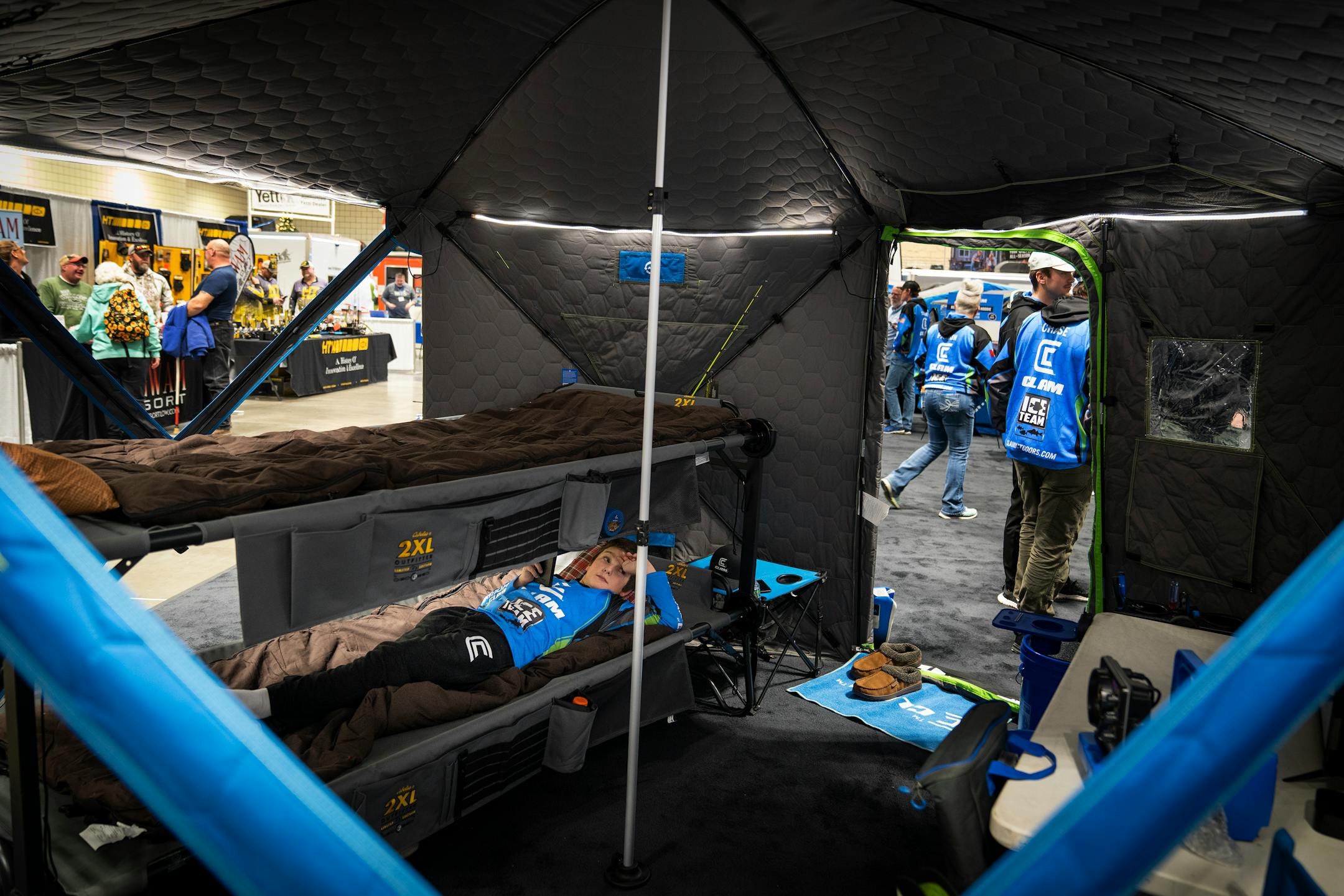 Ben Johnson, son of Matt Johnson, the pro staff director of Clam Outdoors, rests inside one of the Clam Thermal Hub Shelters at the St. Paul Ice Fishing and Winter Sports Show in St. Paul, Minn. Friday, Dec. 1, 2023. ] LEILA NAVIDI • leila.navidi@startribune.com