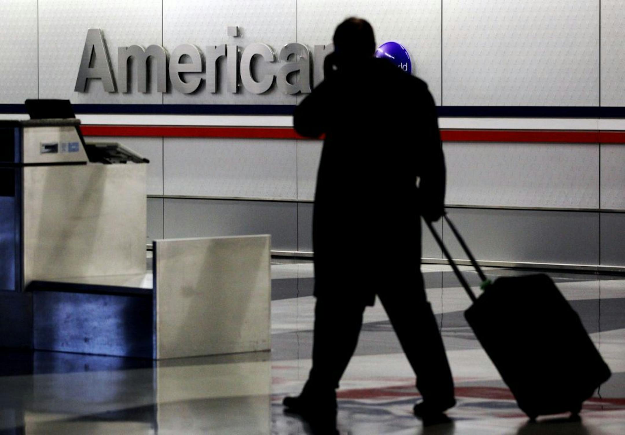 FILE - In this Tuesday, Nov. 29, 2011, file photo, a passenger walks through an American Airlines baggage claim area at O'Hare International Airport in Chicago Tuesday, Nov. 29, 2011. American Airlines said Thursday, May 16, 2013, that people carrying just a personal item that fits under the seat, not a rolling suitcases, will be allowed to board before most other passengers. American said that the change will speed up the boarding process and allow flights to take off sooner, helping the airlin