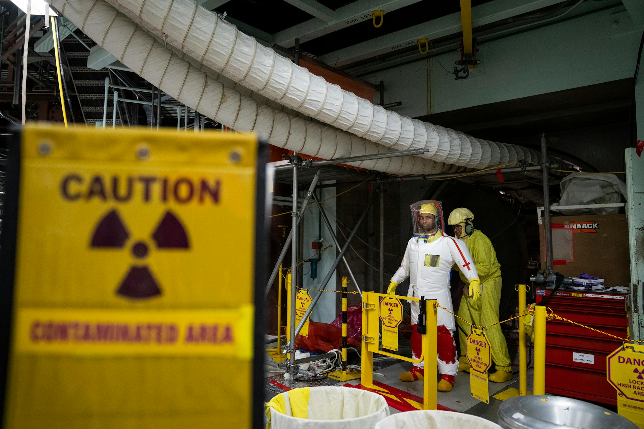 Nigel Hester, in white, an under-vessel technician, has his protective layers checked before working on control rod drive replacement inside the reactor building.