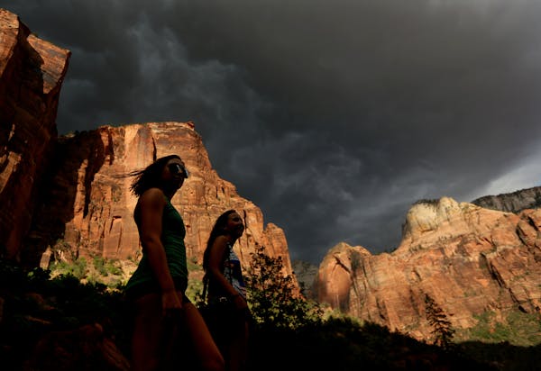 Hikers look up at a fast moving storm as it makes its way through Zion National Park outside of Springdale, Utah.