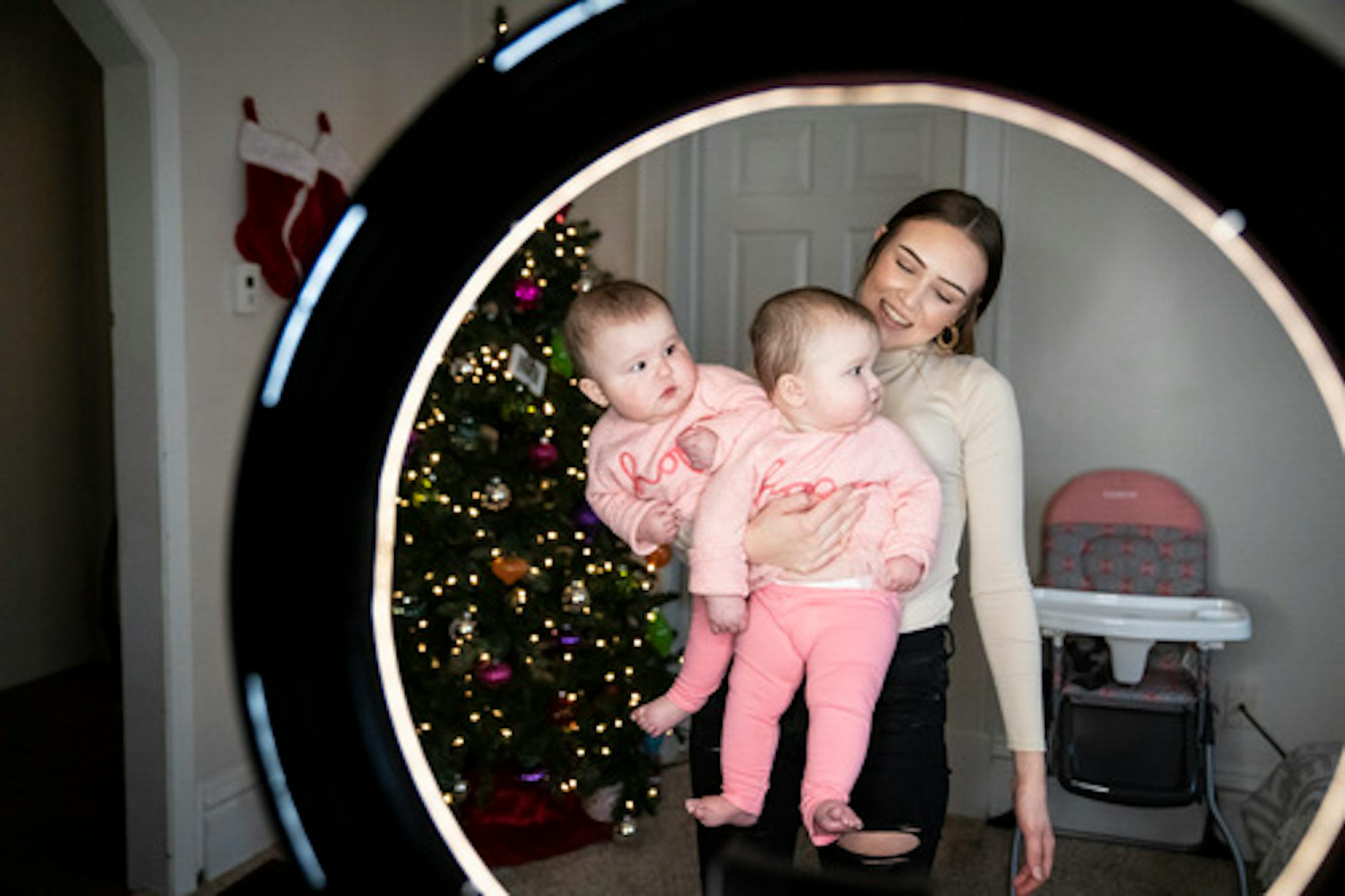 Alexis LaRue holds both her twins, Camila &amp; Elena Mejia, in one arm in tribute to the first TikTok video she did that went viral, at home on Thursday, Nov. 18, 2021, in St. Paul, Minn. LaRue has become TikTok famous, with more that 800k subscribers, for videos with her 8-month-old twins. She is photographed through the ring light she uses to record most of her videos. ] RENEE JONES SCHNEIDER • renee.jones@startribune.com