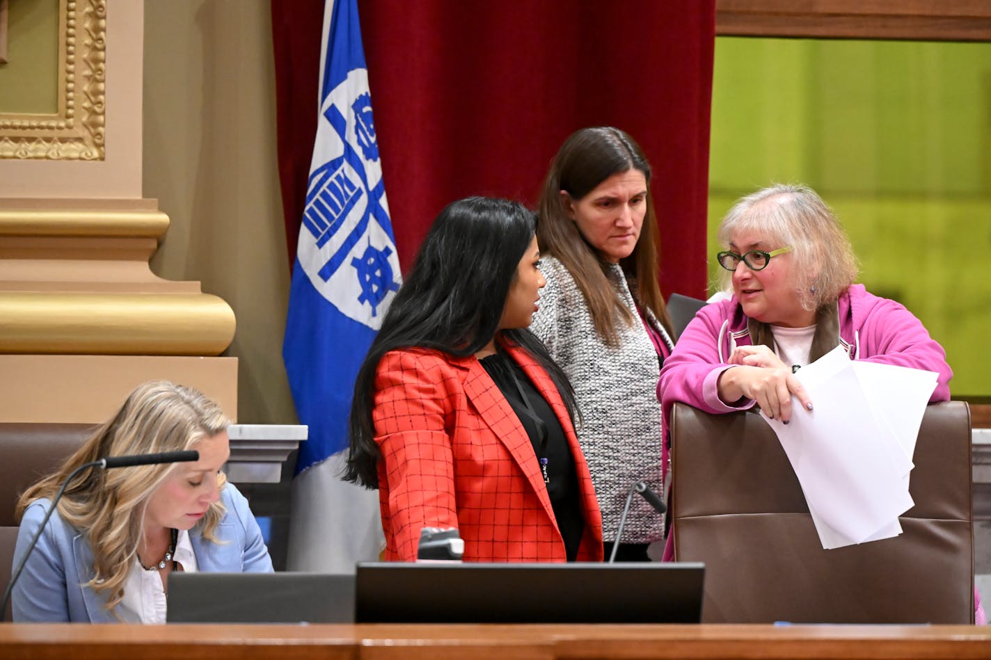 Minneapolis City Council Members Aurin Chowdhury, center, and Lisa Goodman talk as Linea Palmisano listens while Budget Committee Chair Emily Koski, left, worked during a lunch recess Friday.