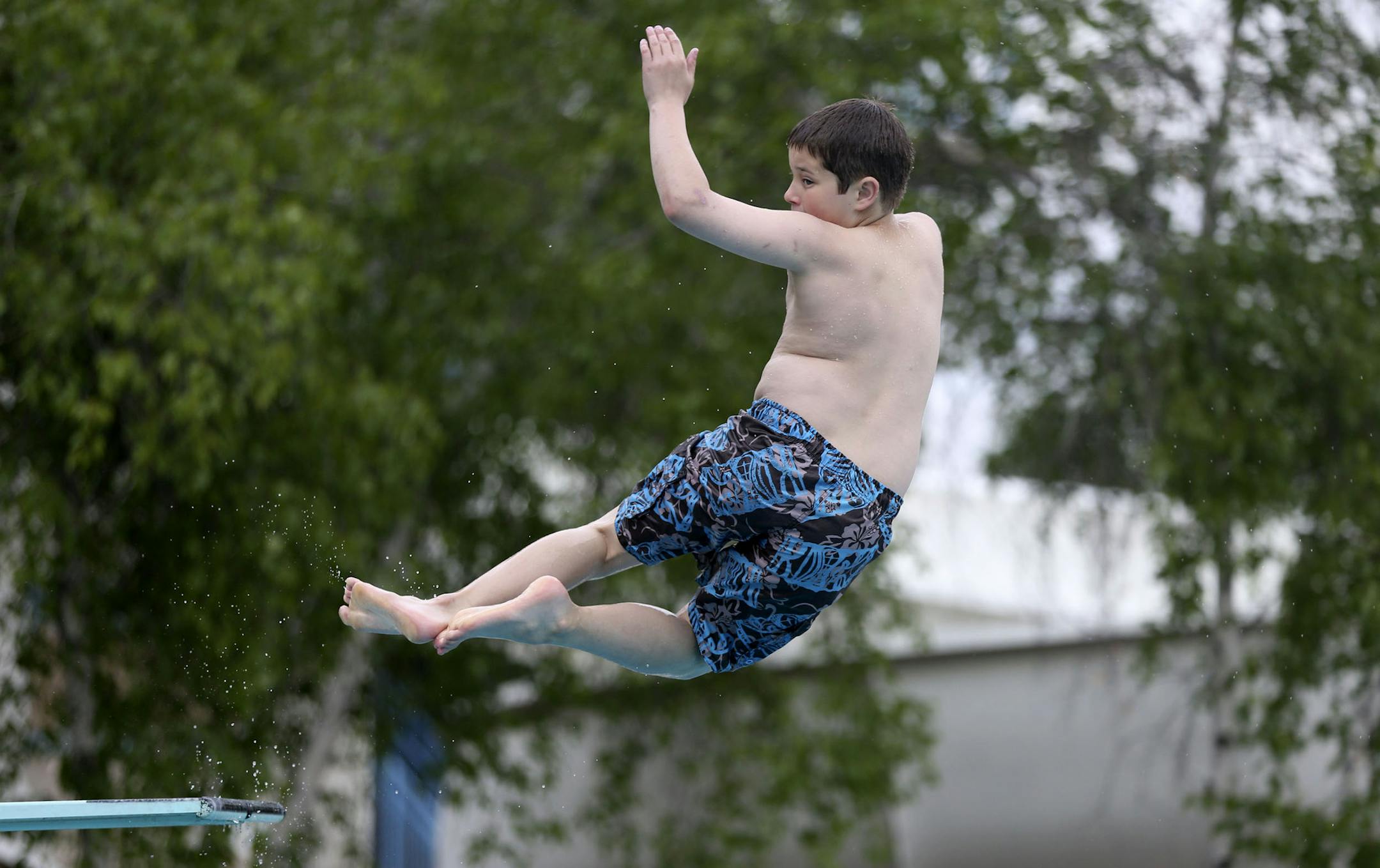 Logan Gefre, 12, jumped off the diving board and was having fun despite the dreary weather on opening day at the St. Louis Park Outdoor Aquatic Park in St. Louis Park, Min., Friday, June 7, 2013. ] (KYNDELL HARKNESS/STAR TRIBUNE) kyndell.harkness@startribune.com