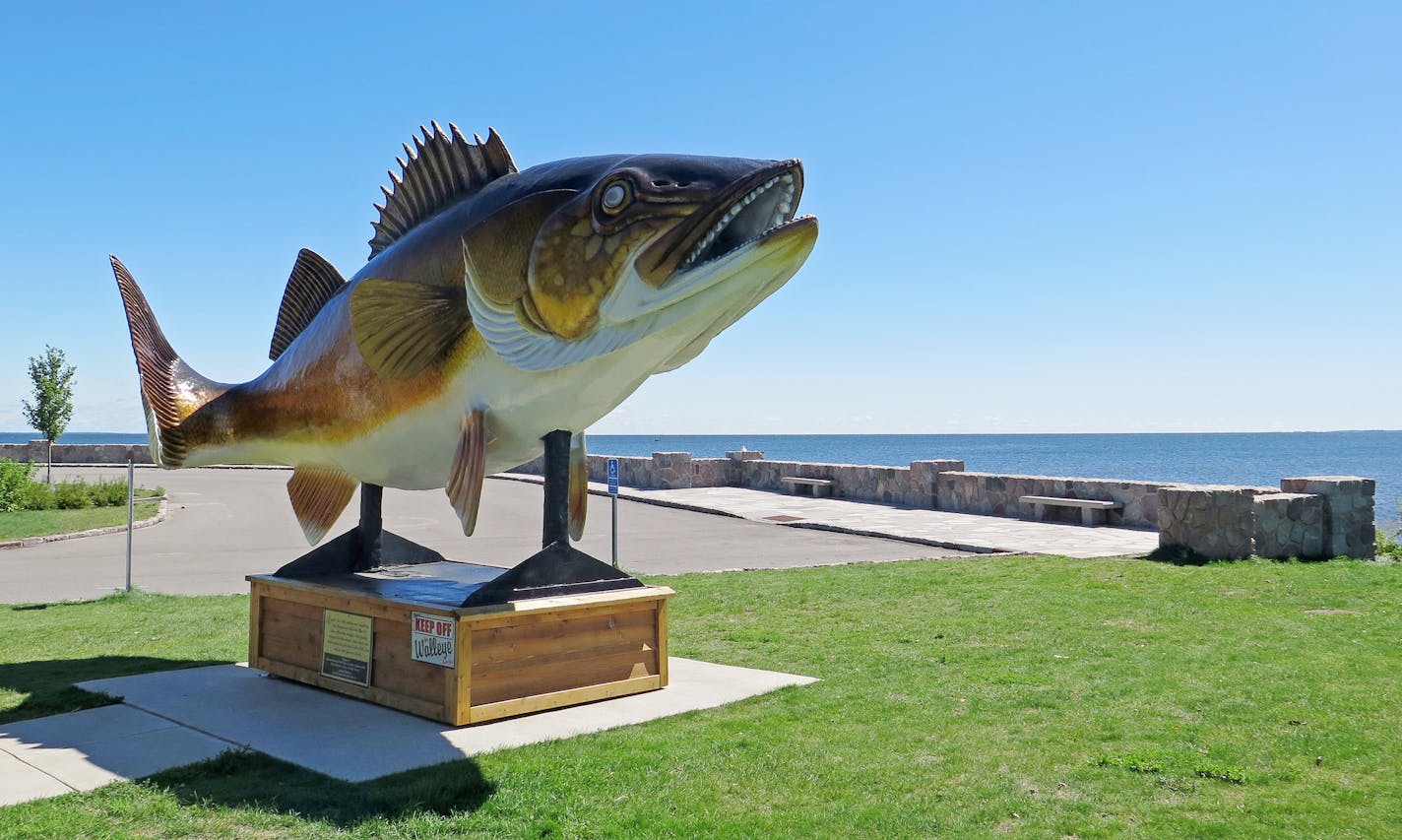 FILE - In an Aug. 25, 2015, file photo, a walleye statue in Garrison, Minn., sits next to Lake Mille Lacs. Mille Lacs had been one of Minnesota's most popular fishing destinations, but the lake's changing ecosystem has contributed to a sharp decline in its walleye population, though its bass and northern pike are doing well. (Tom Scheck/Minnesota Public Radio via AP) MANDATORY CREDIT